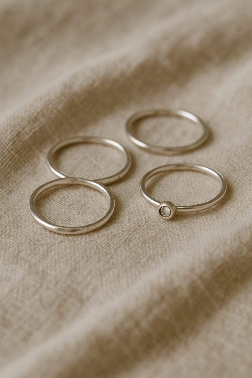Delicate handcrafted silver rings arranged on a linen cloth