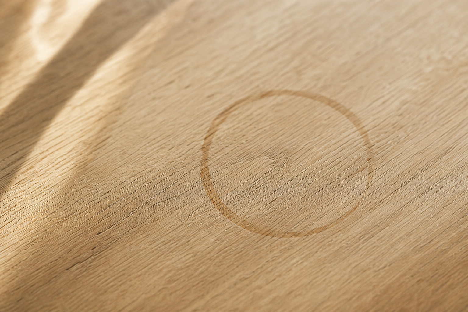 Macro shot of light oak wood table grain with a faint coffee cup ring