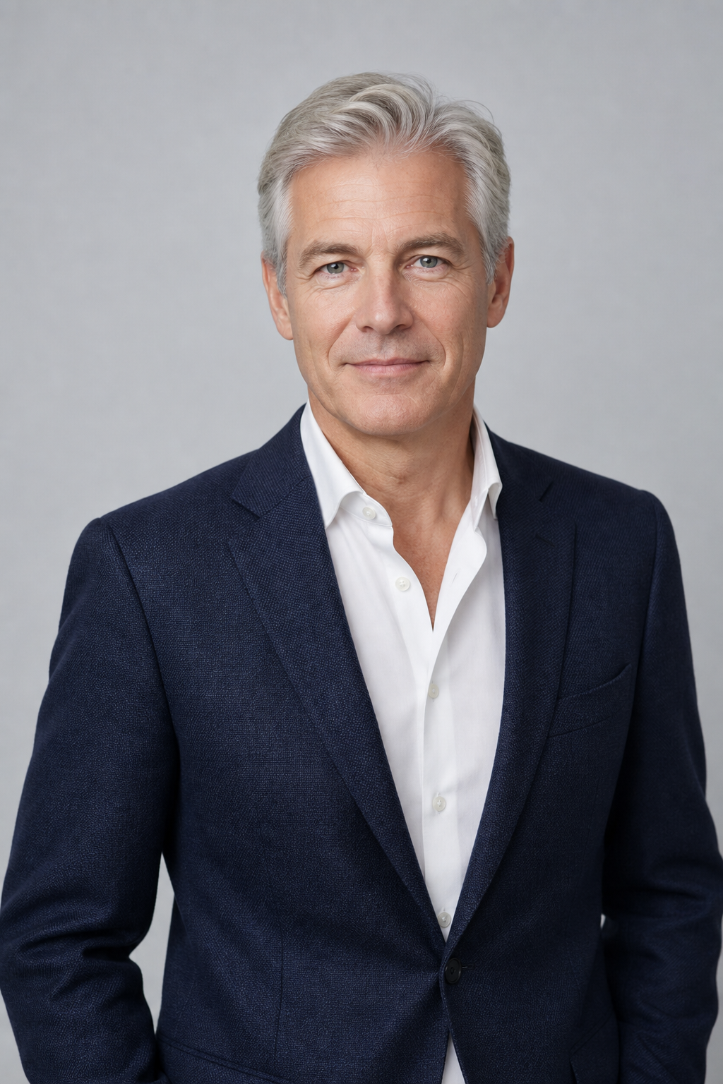 Contained portrait of a male clinical development leader with light skin and silver hair wearing a navy jacket