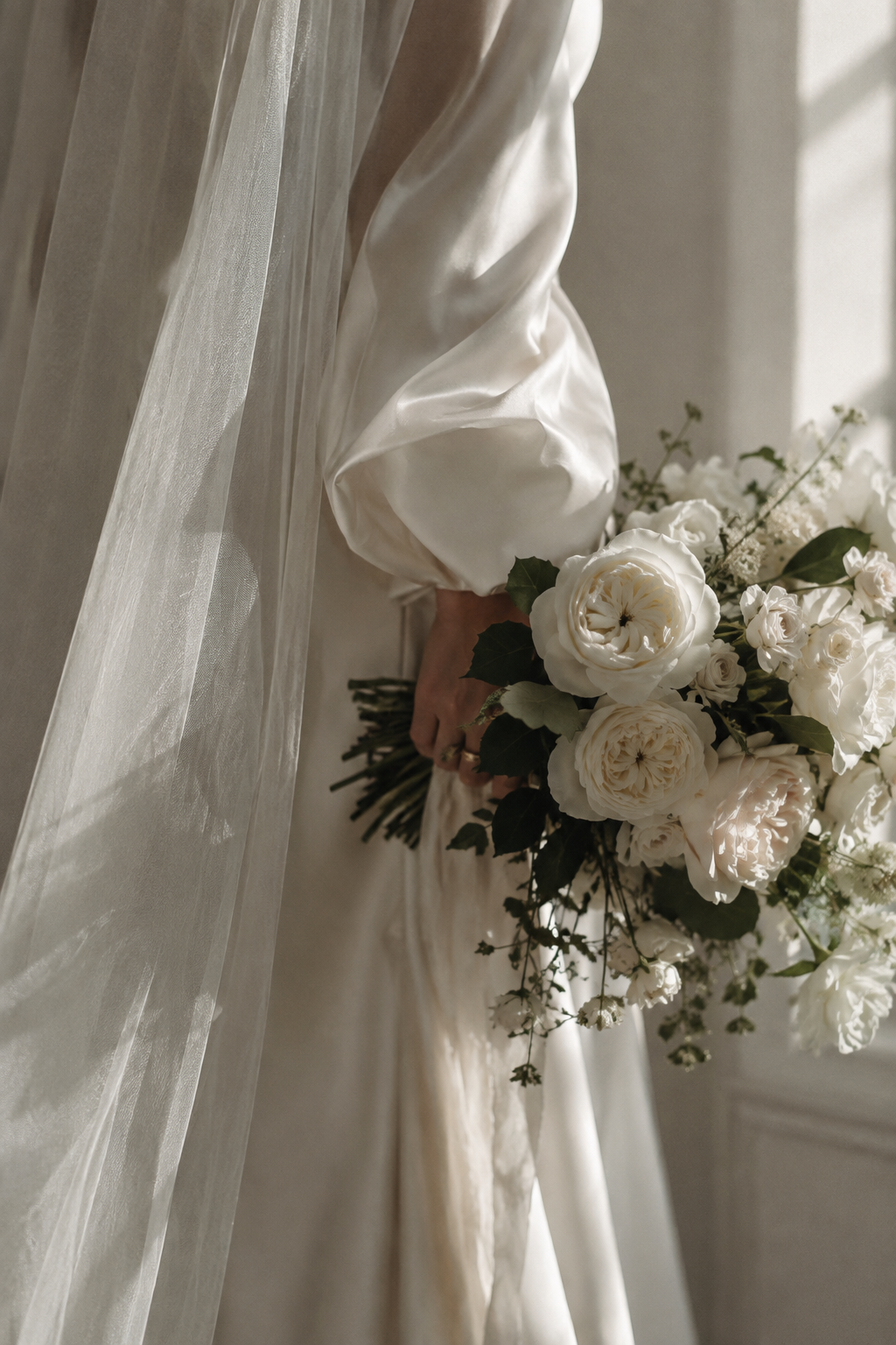 Bride holding a white garden rose bouquet beneath a sheer silk veil