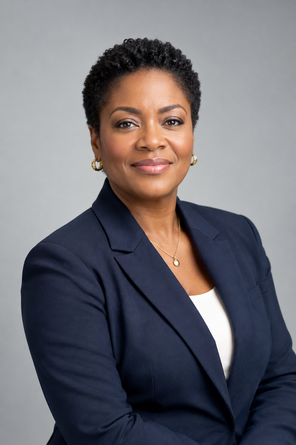 Confident middle-aged Black woman executive in a tailored navy blazer, studio portrait with soft neutral background