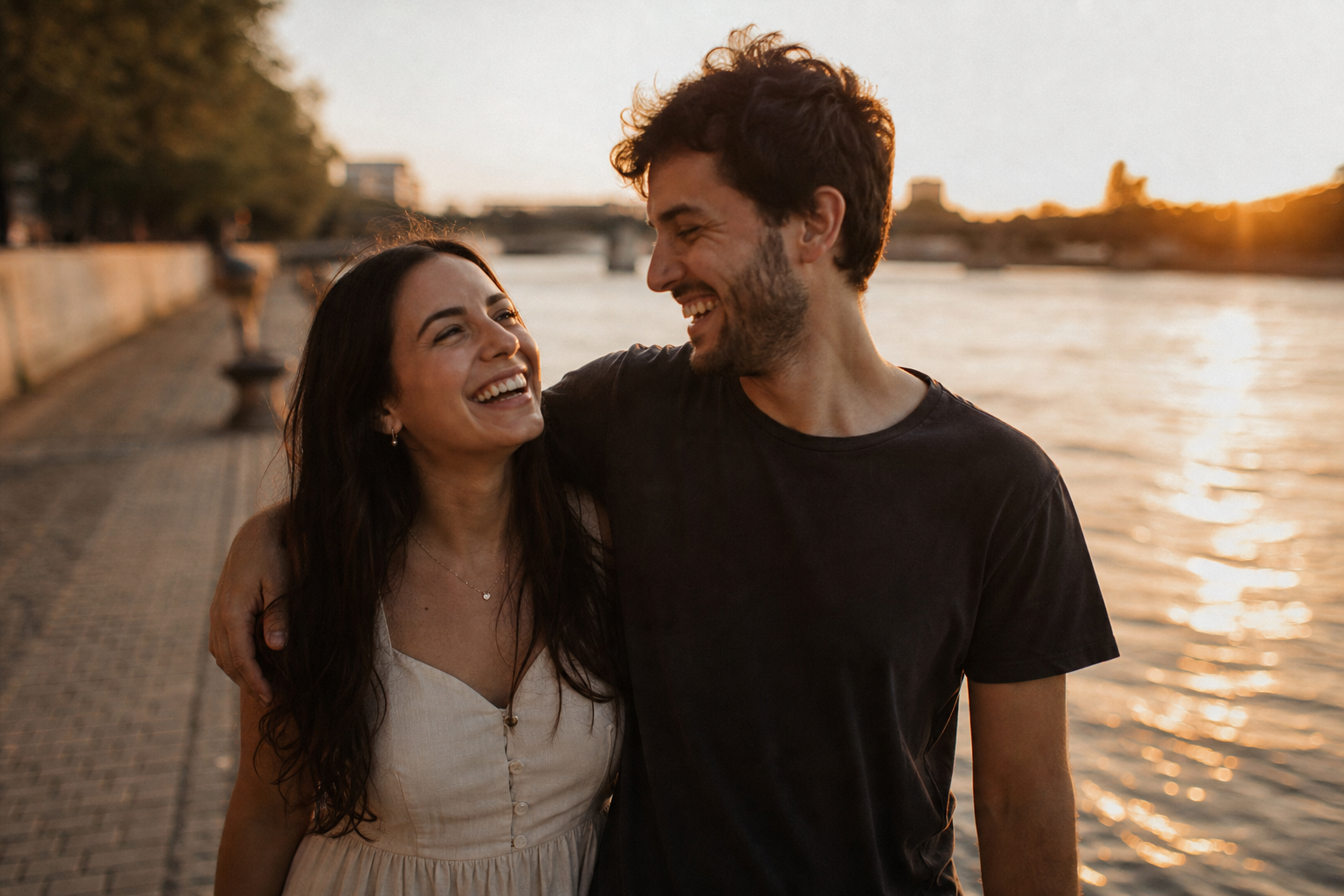 Afonso and Iara laughing together by a riverside at sunset