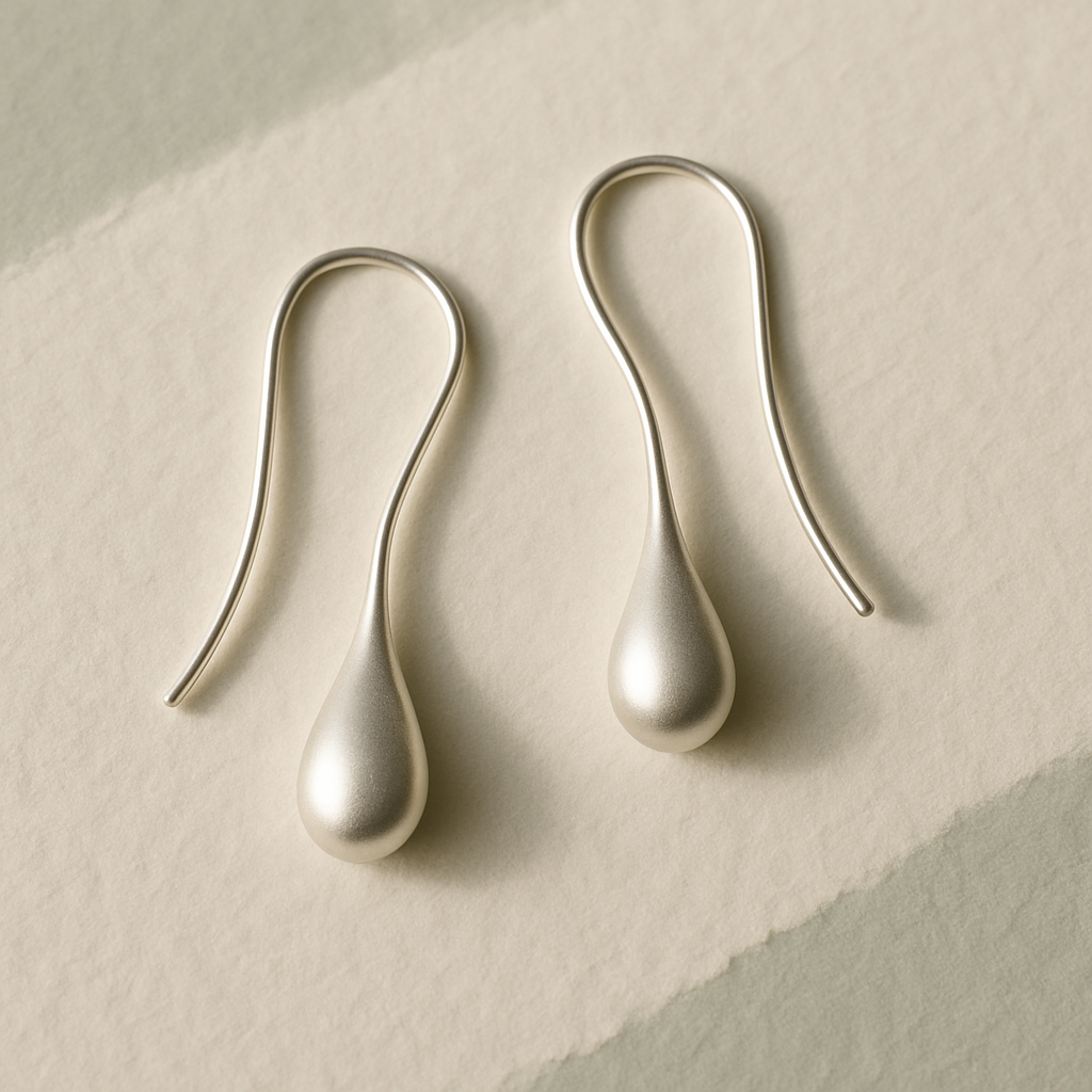 Delicate silver earrings on textured paper
