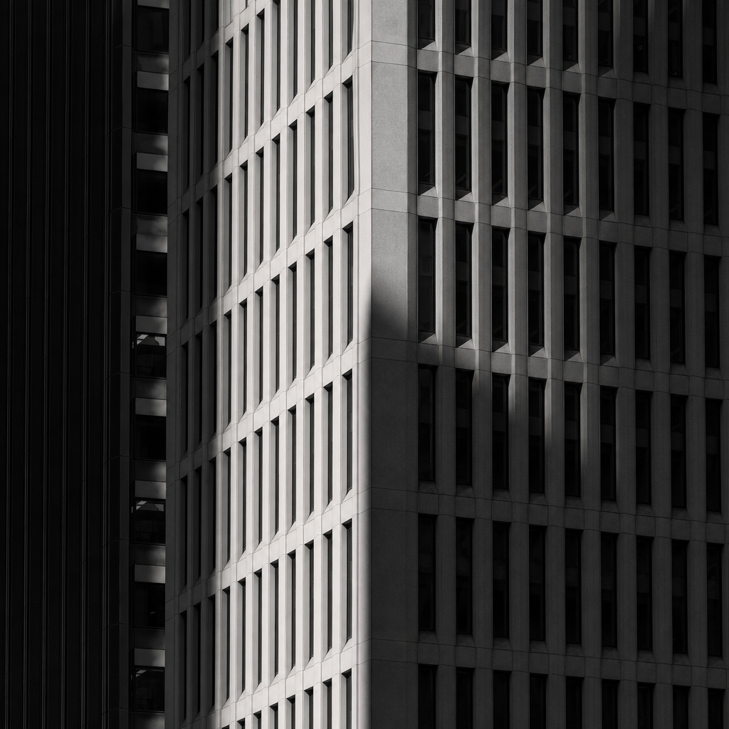 Monochrome city tower crop with repeating windows and deep shadows