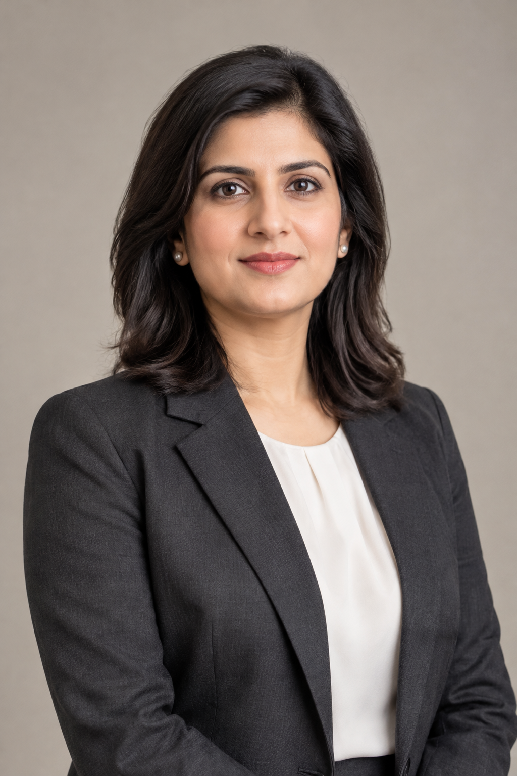 Professional portrait of Advocate Sara Khan in a charcoal blazer with a light shirt against a soft grey studio backdrop