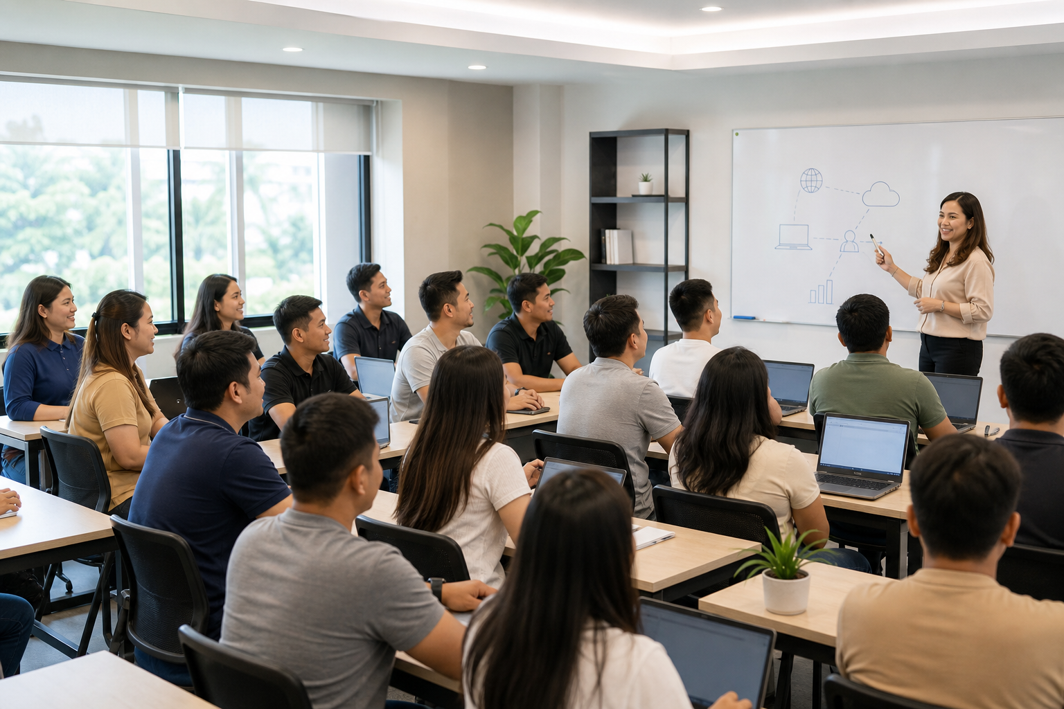 Female Filipino instructor leading a larger mixed-gender group of Filipino adult students in a modern vocational classroom with laptops, whiteboard teaching, and welcoming collaborative learning