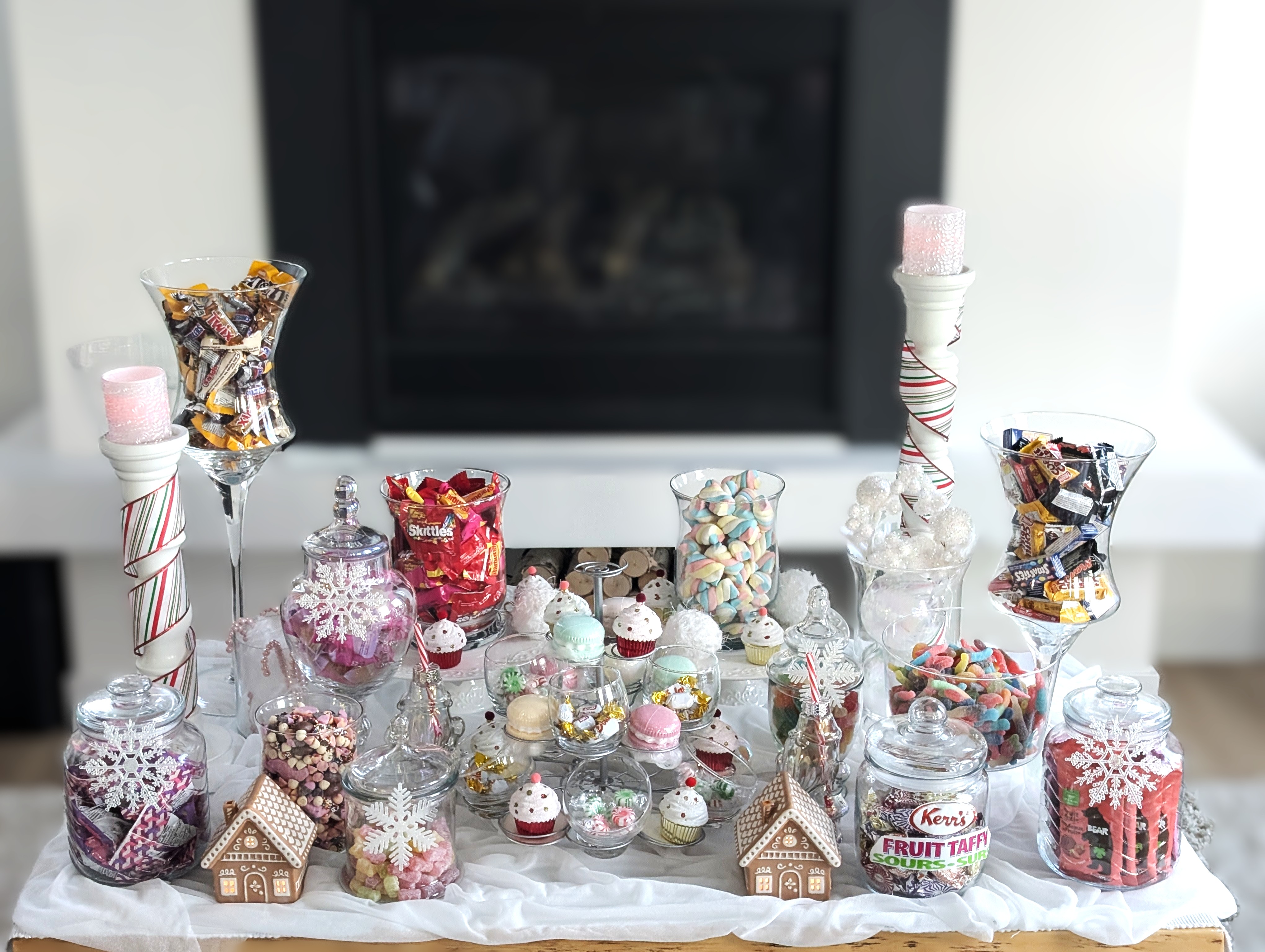 Holiday-styled candy buffet with glass jars and sweets on white draped fabric