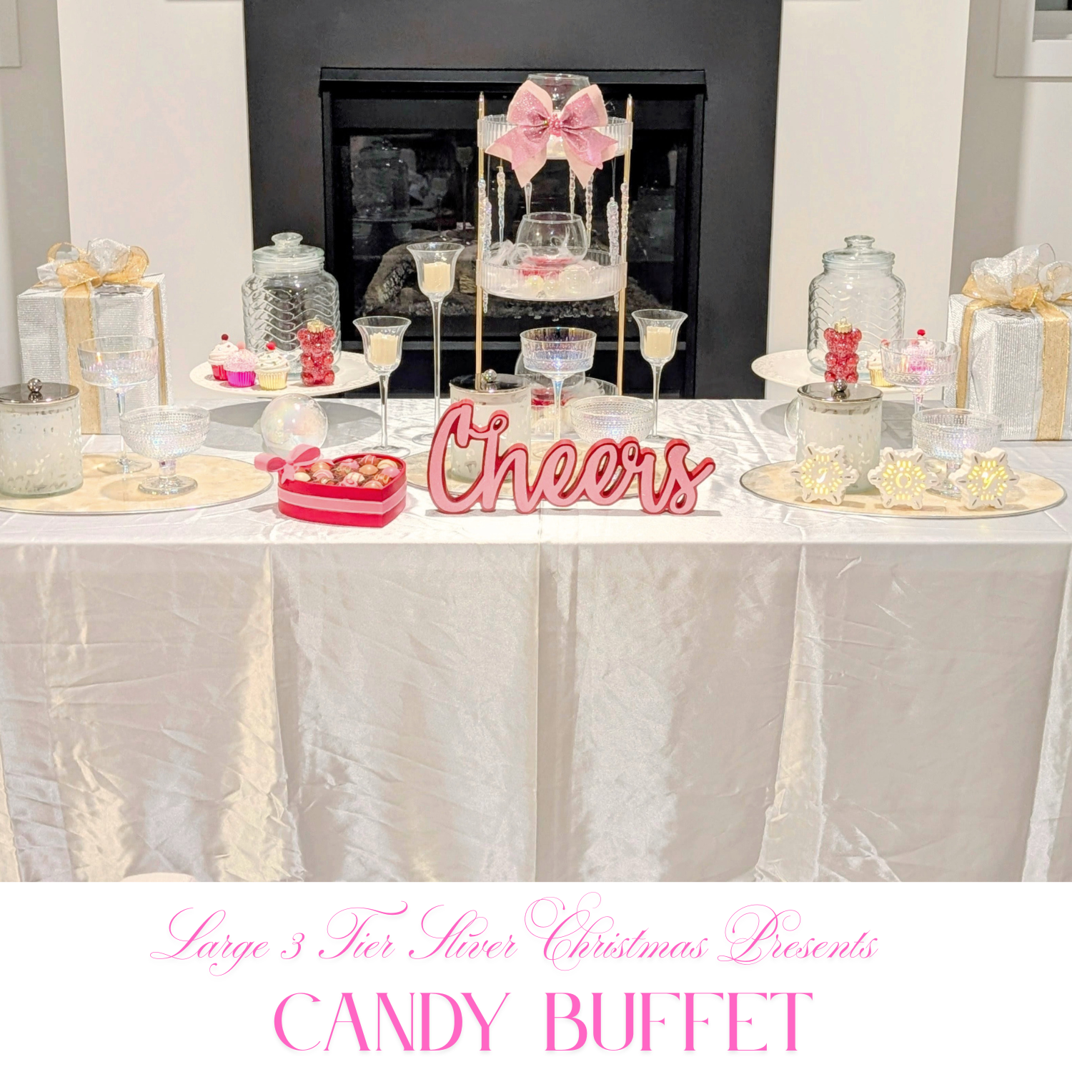 Pink-accent Christmas candy buffet with a three-tier stand, glass jars, wrapped gift boxes, and a Cheers centerpiece