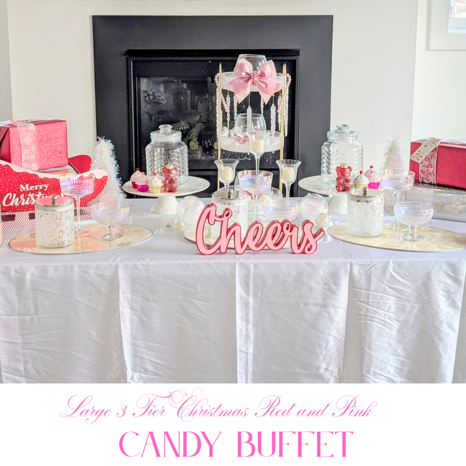 Christmas candy buffet in pink and red tones with a central Cheers sign, glass serving bowls, and gift box accents