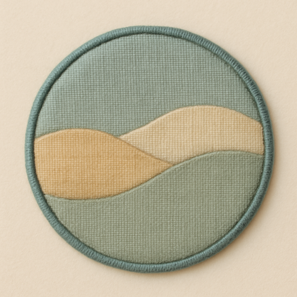 Soft, muted Kinusaiga-style fabric emblem in gentle teal, pale honey, and quiet sage tones with a delicate teal border, showing a refined handcrafted textile texture