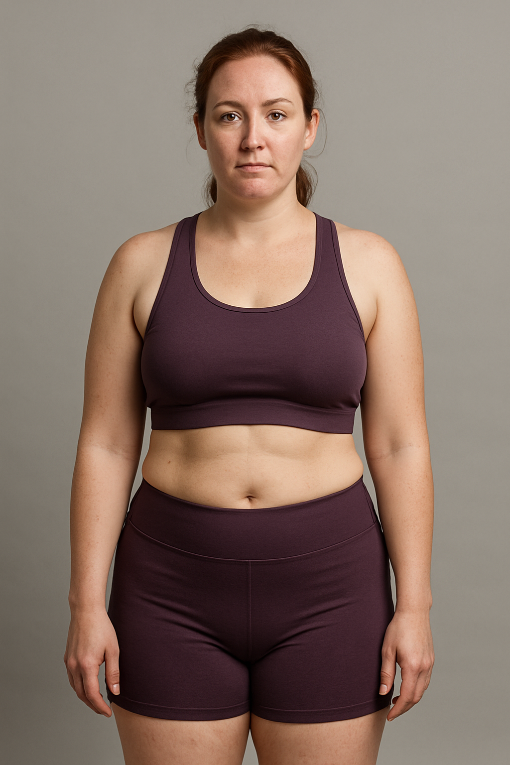 Illustrative starting-point portrait of a woman with auburn hair wearing a plum training set