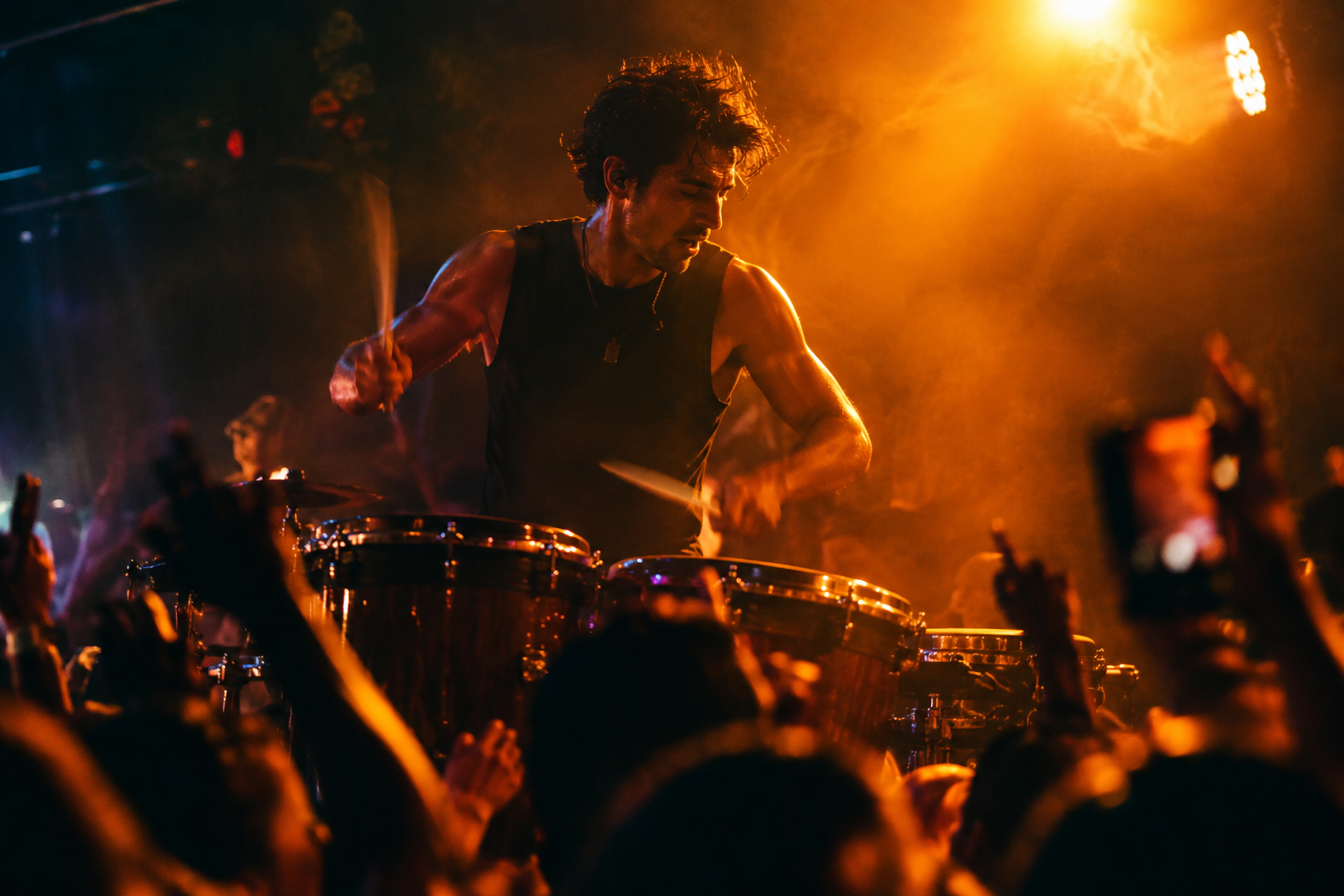 Live percussion performer under amber spotlight with motion blur sticks and crowd silhouettes