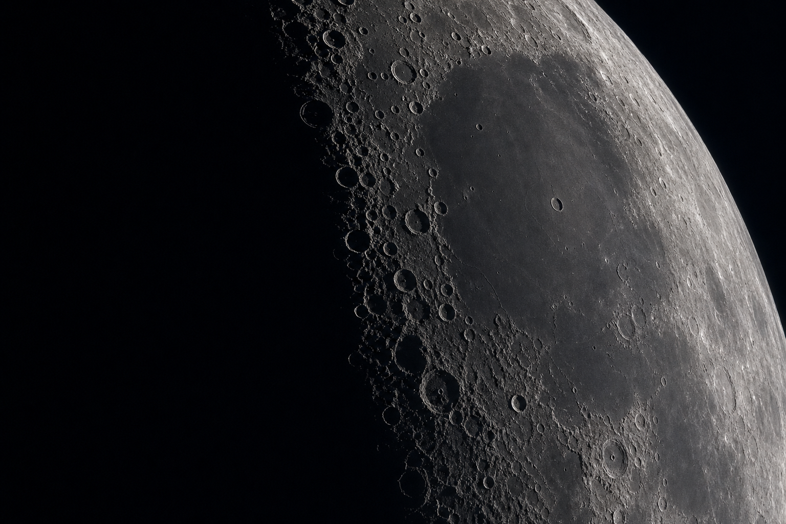 Monochrome telescopic close-up of the Moon's terminator near Mare Imbrium with crisp crater shadows