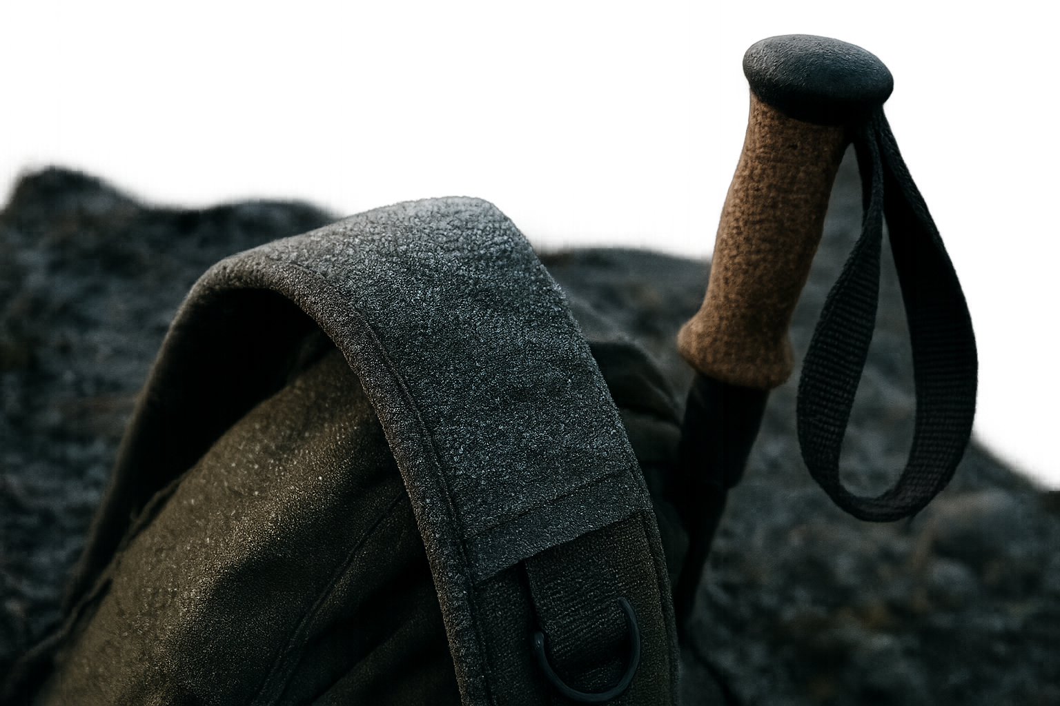 Close trail detail showing frost on a rugged hiking backpack strap and trekking pole handle at dawn