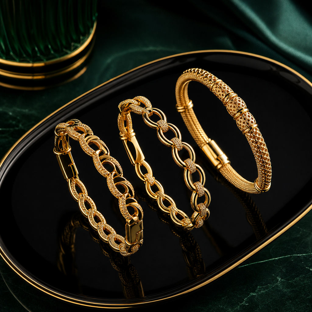 Gold bracelet trio with intricate textures displayed on a glossy black tray