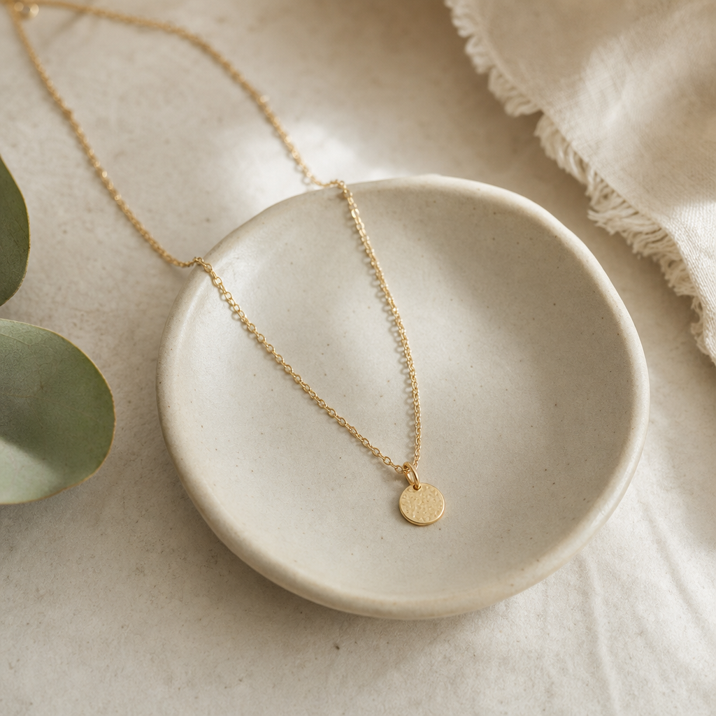 Delicate gold necklace draped over a ceramic dish