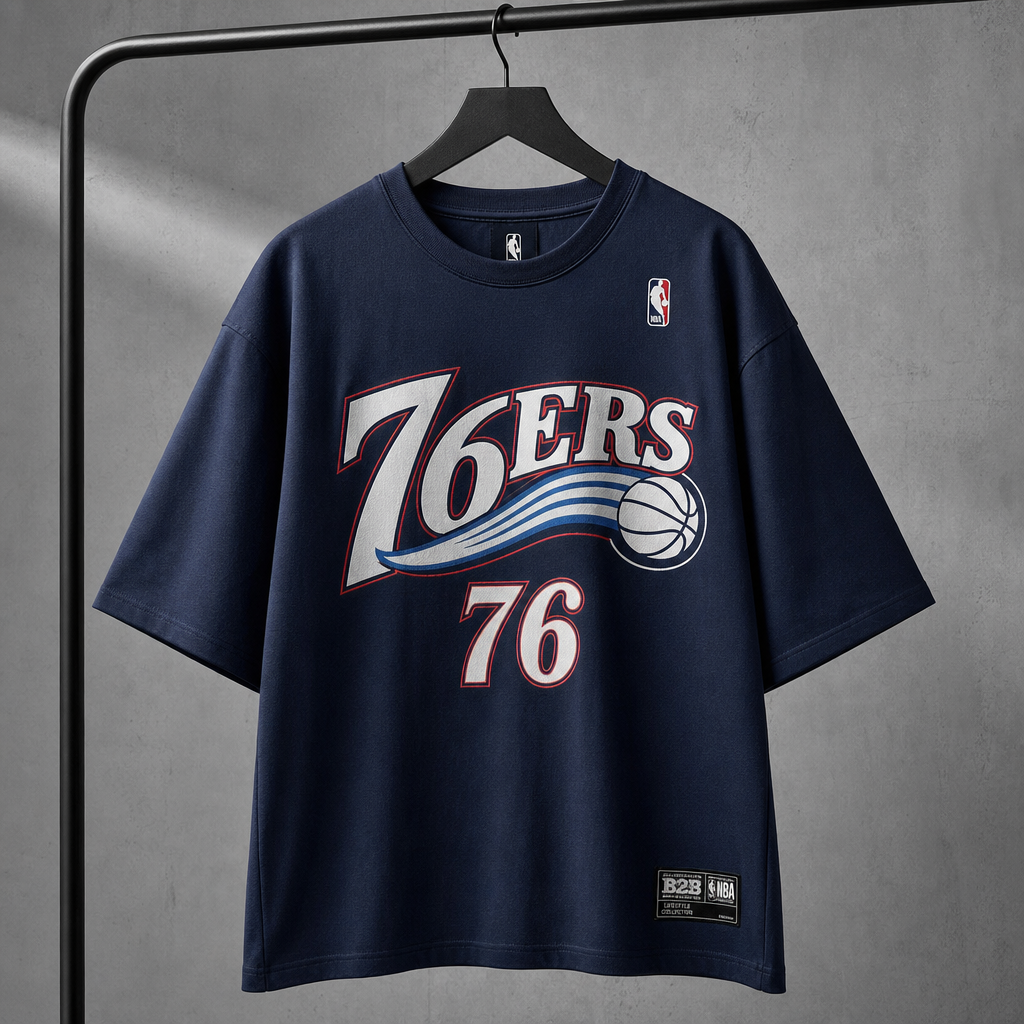 Camiseta azul de 76ers — Cuello redondo, colgada en percha, gráfico frontal centrado.