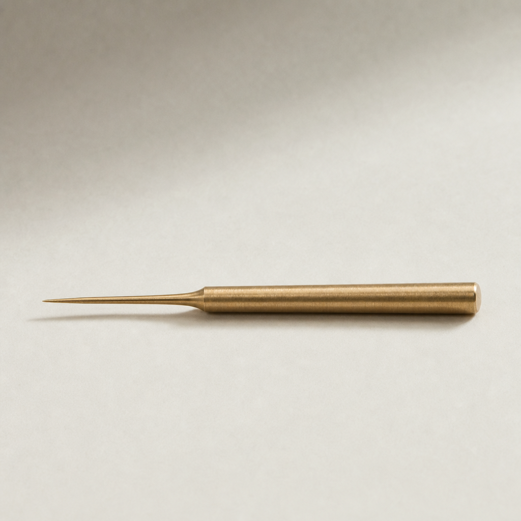 Slender brushed brass tea needle with a pointed tip and matte golden finish presented horizontally