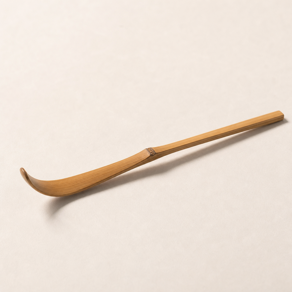 Bamboo tea scoop resting on a neutral surface with soft shadow