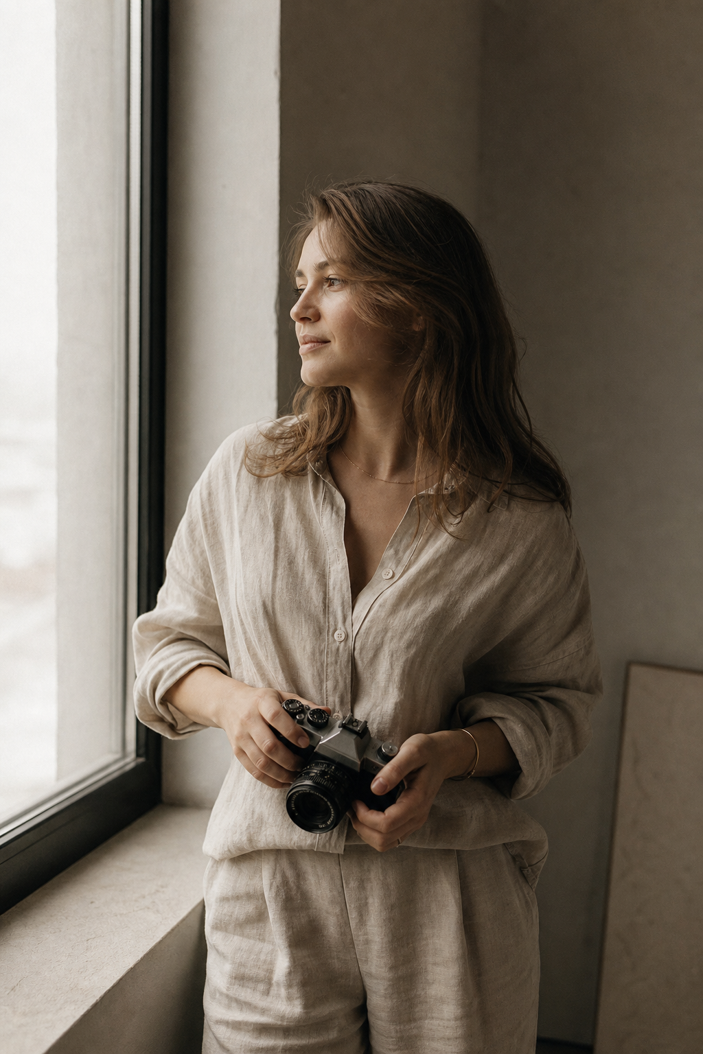 Portrait of photographer Iryna Kovalenko holding a camera in soft natural light