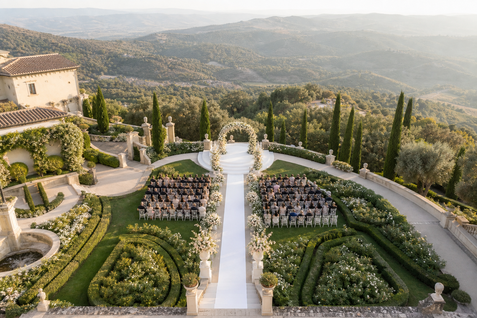 Elegant hillside estate ceremony setup seen from above with white aisle and seated guests