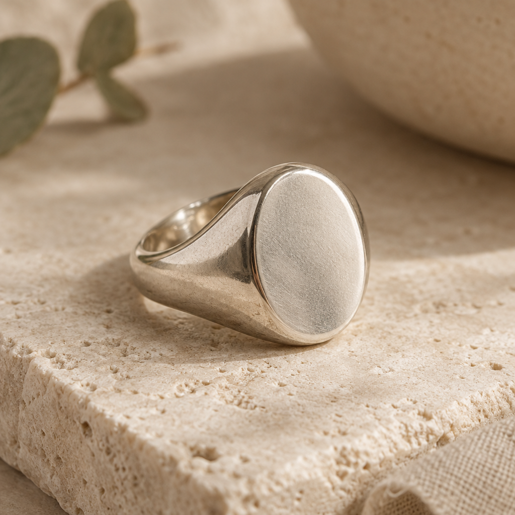 Sculptural sterling silver signet ring with a softly polished oval face on pale textured stone