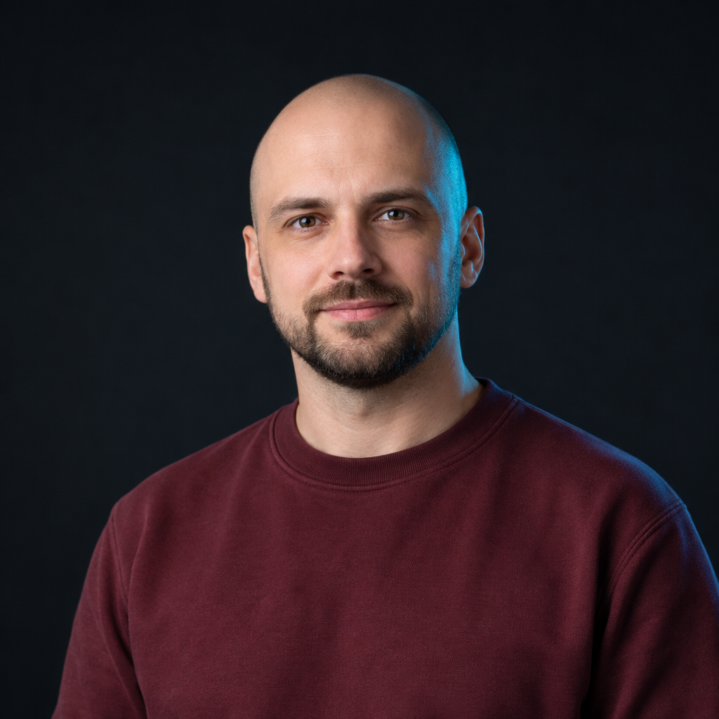 Maksym Shevchenko, with a shaved head, short beard, and burgundy sweatshirt