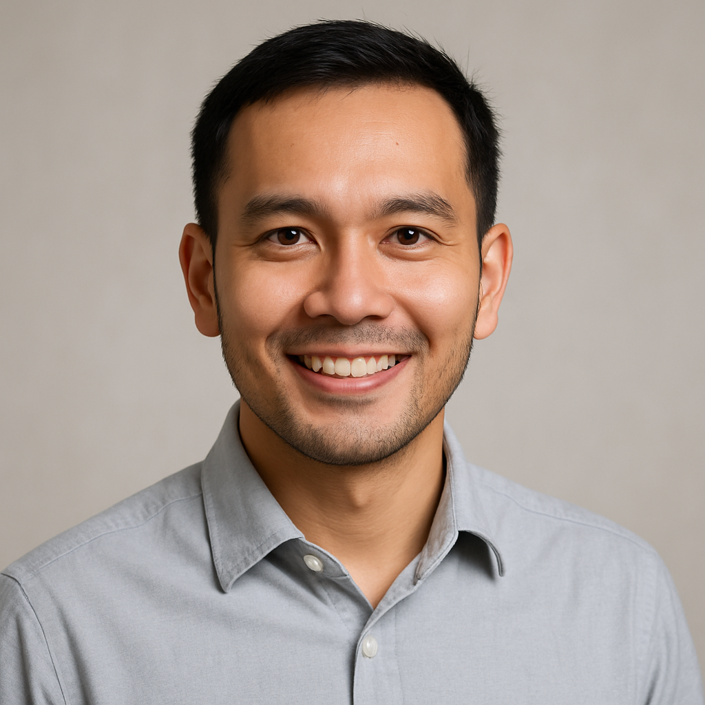 Portrait of a Malaysian man in his mid 30s with short black hair and light stubble, wearing a light grey shirt and a confident smile.
