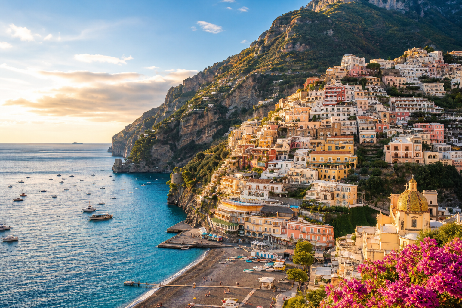 Sunlit cliffside villages above the turquoise Amalfi Coast with boats in a calm bay