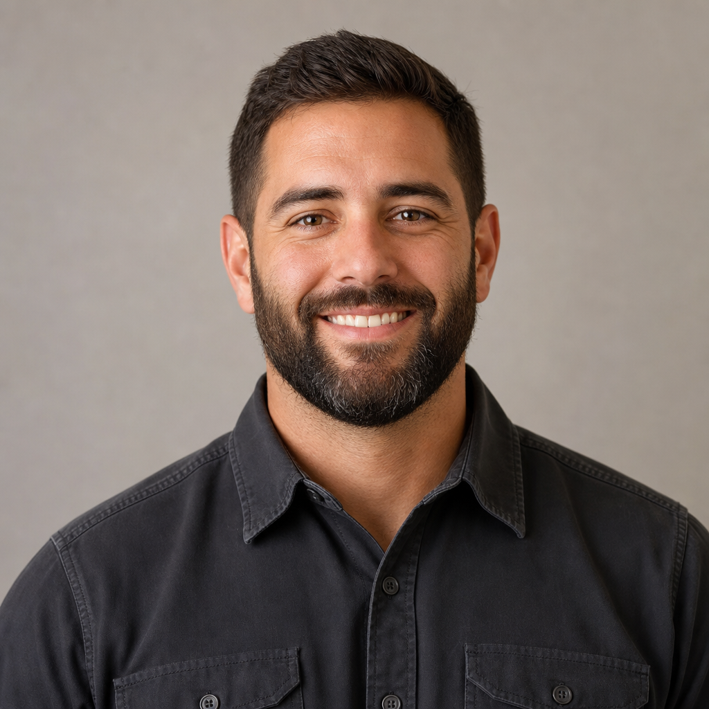 Portrait of a bearded man in a charcoal work shirt smiling