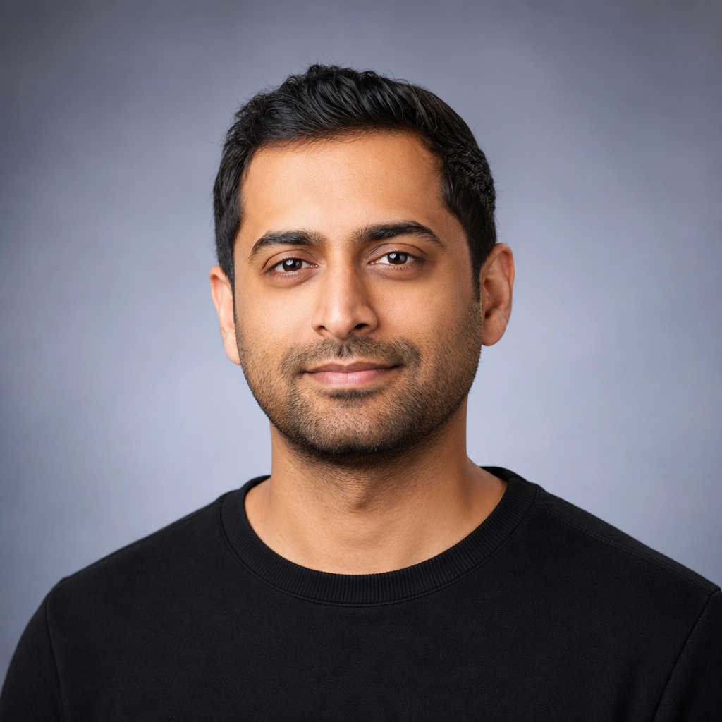 South Asian man in his 30s with short hair wearing a black crewneck, professional headshot