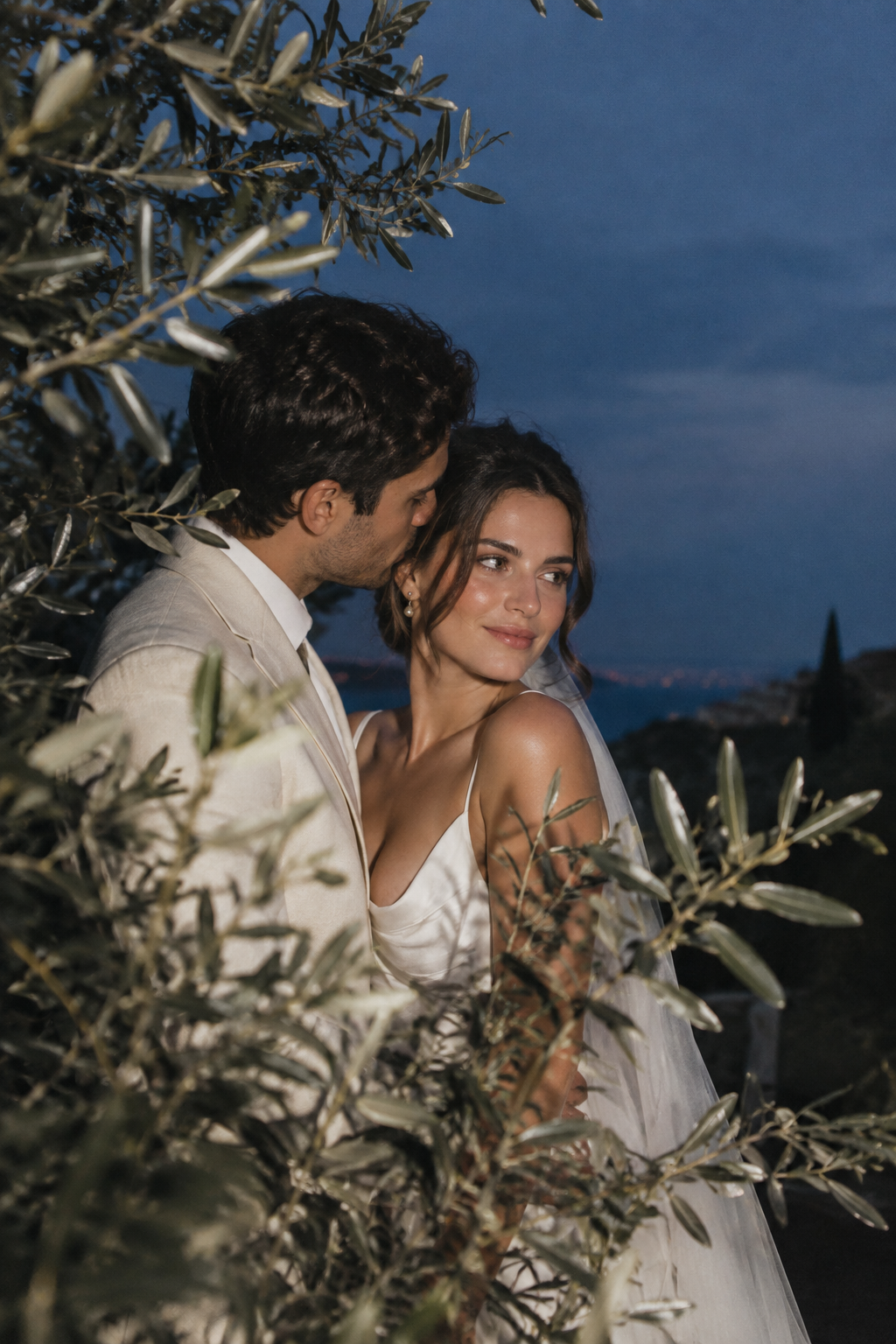 Evening portrait of a couple framed by olive trees and fading sky