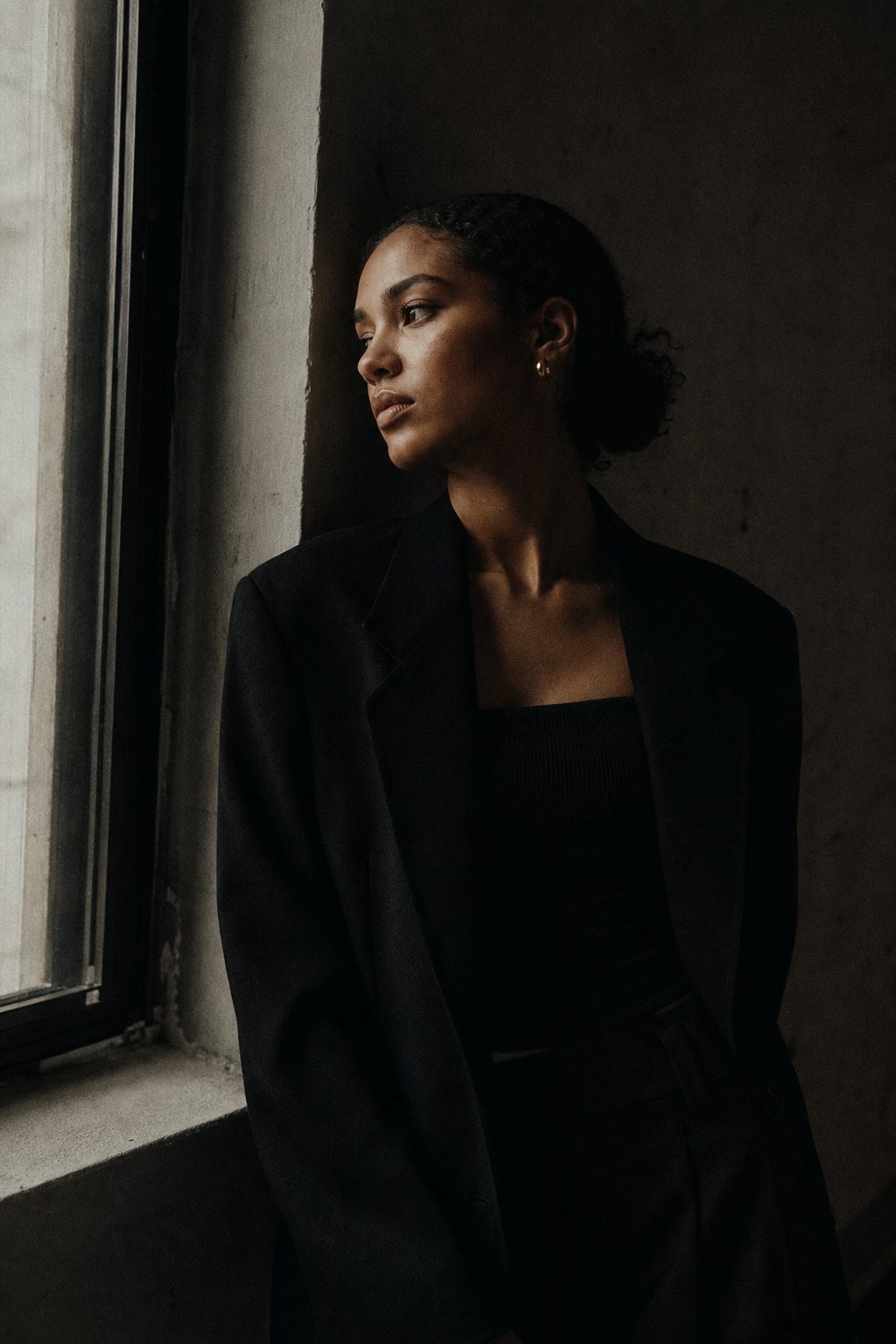 Moody analog-style portrait in soft window light with visible 35mm grain, gentle contrast, and intimate cinematic framing