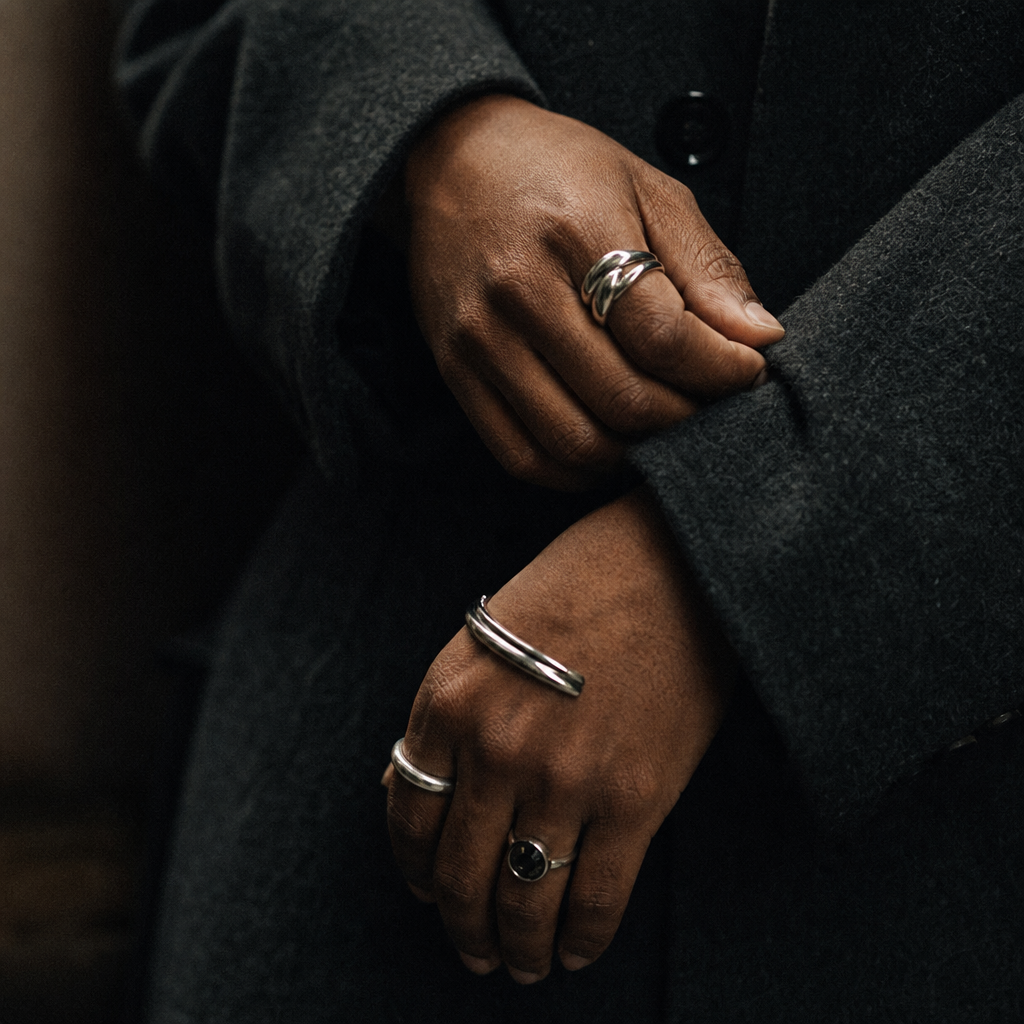grainy film close-up of hands adjusting a coat sleeve with jewelry detail