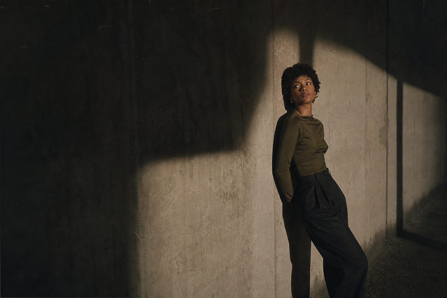 wide 35mm editorial scene with textured wall, soft flash falloff, and visible grain
