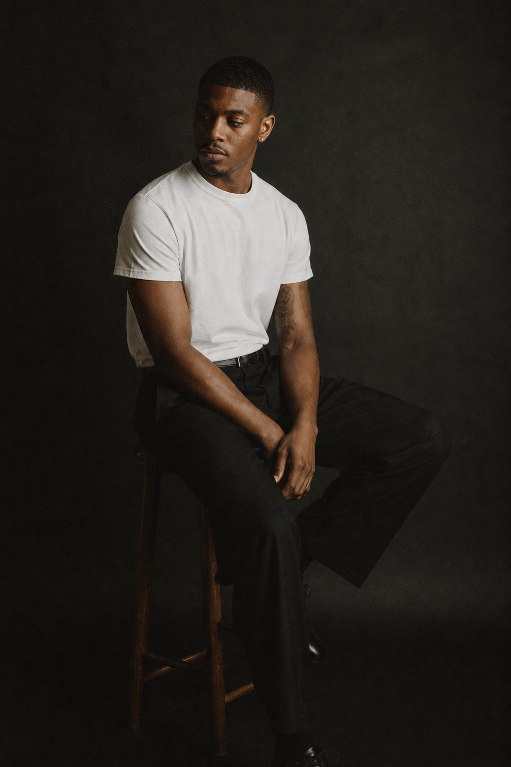 quiet studio 35mm portrait of a man seated against a dark seamless backdrop