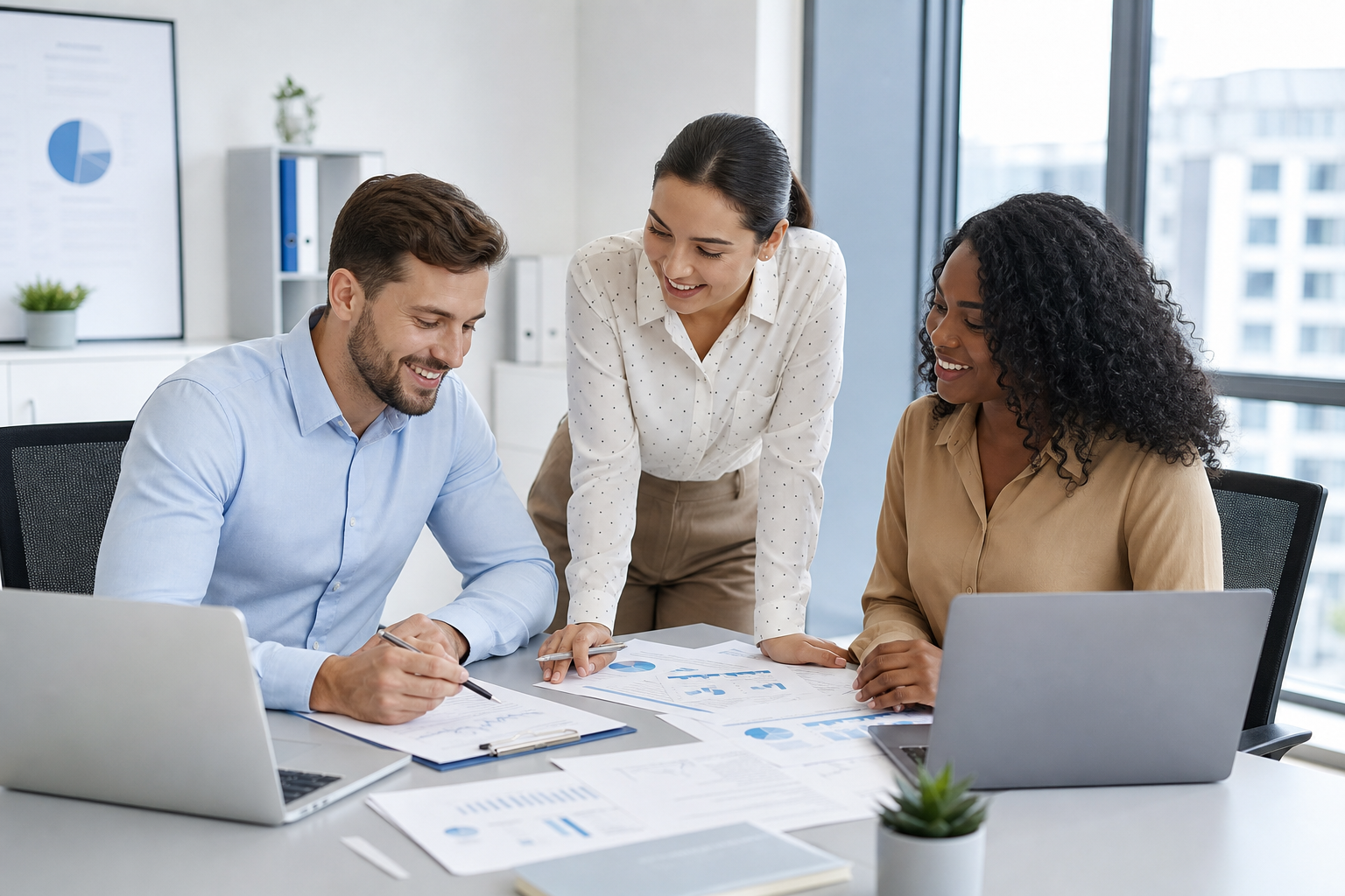 Professional business operations team collaborating at a modern office workstation with laptops and documents