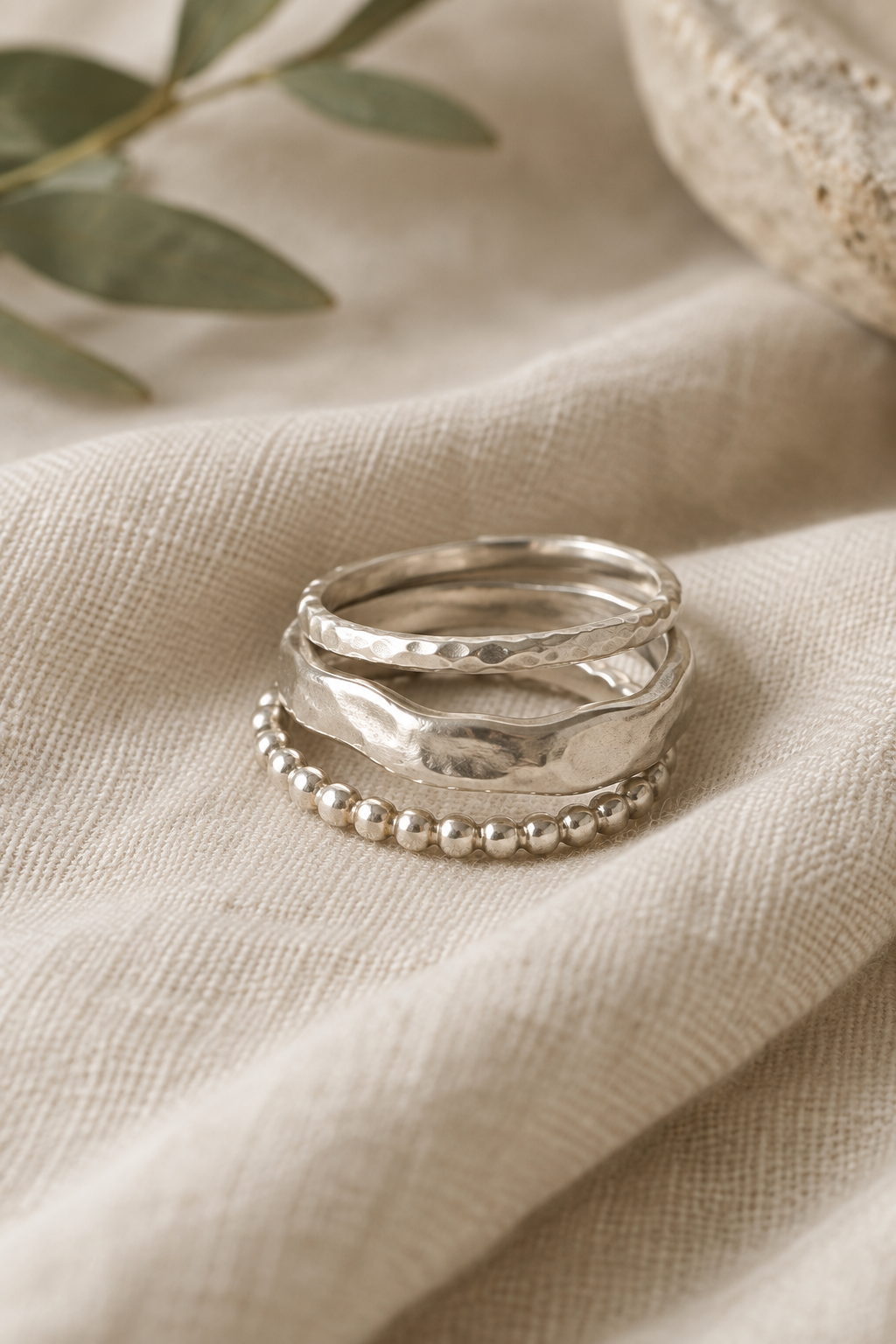 Three softly hammered silver stacking rings on natural linen