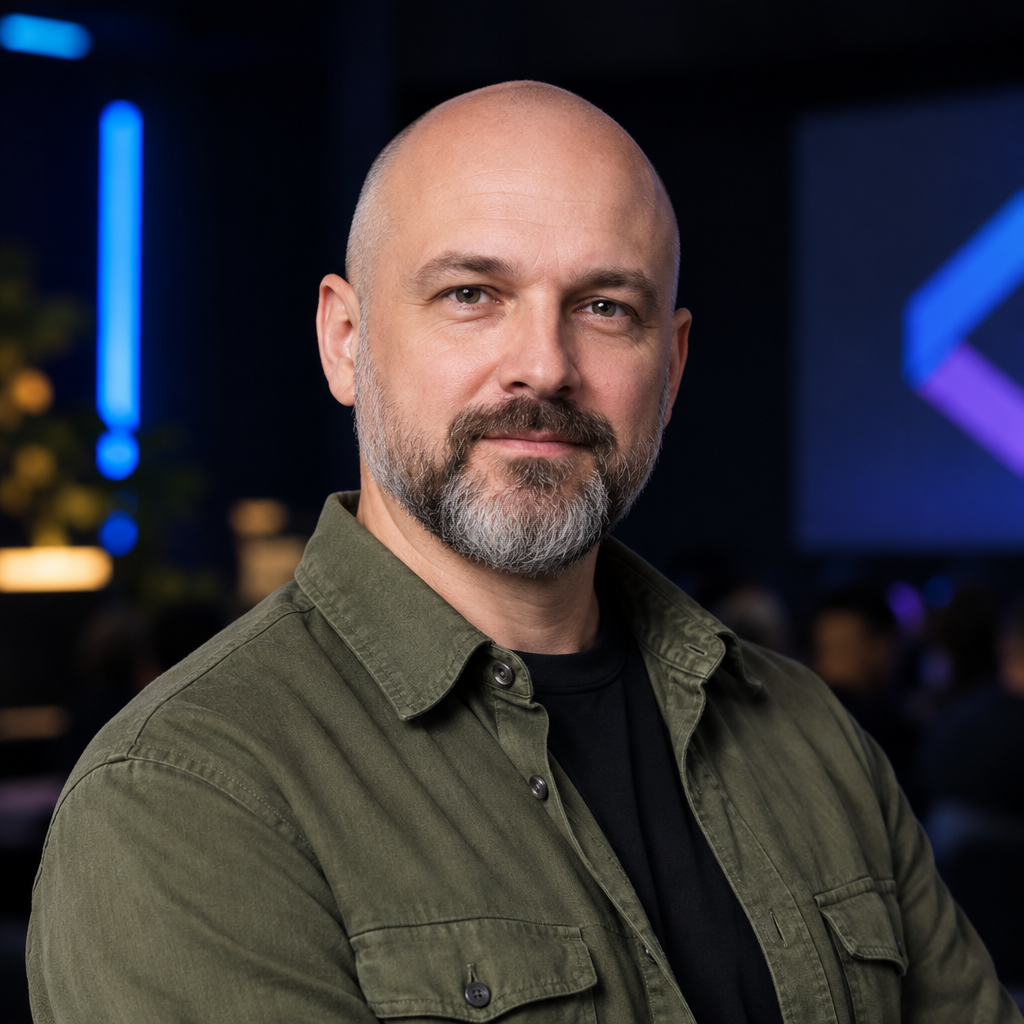 Andrii Hnatiuk, a Ukrainian man with a shaved head and salt-and-pepper beard wearing an olive overshirt, photographed as a conference speaker