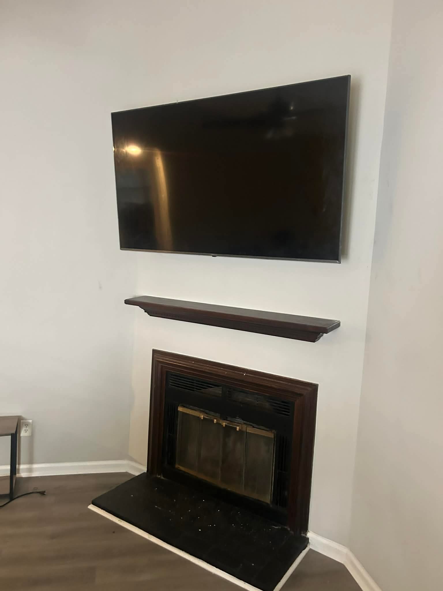 Slim OLED TV mounted on a matte charcoal accent wall with concealed wiring in a Chapel Hill media room