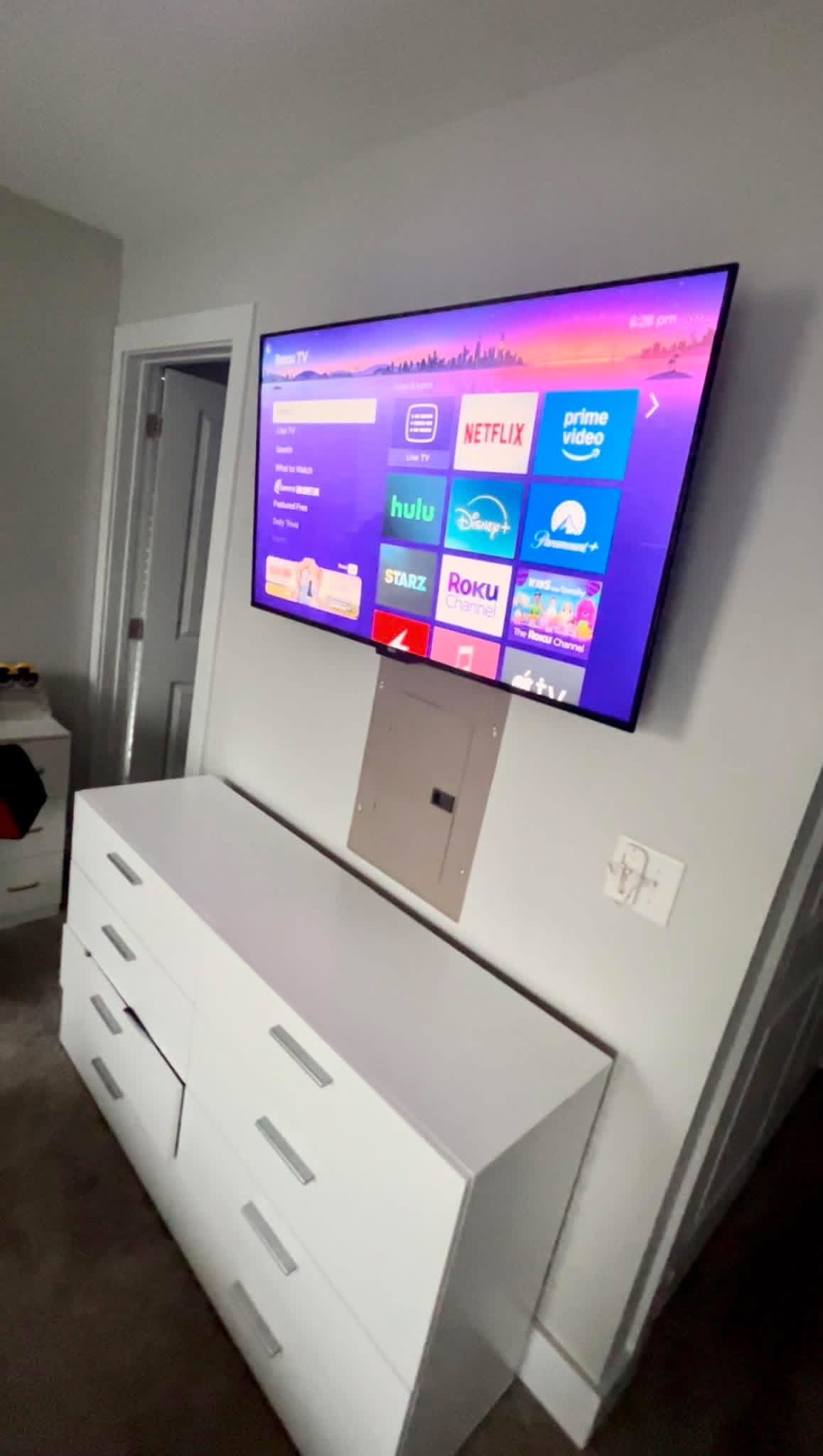 Large frame-style TV mounted over a light stone fireplace with hidden cables in a modern Raleigh living room