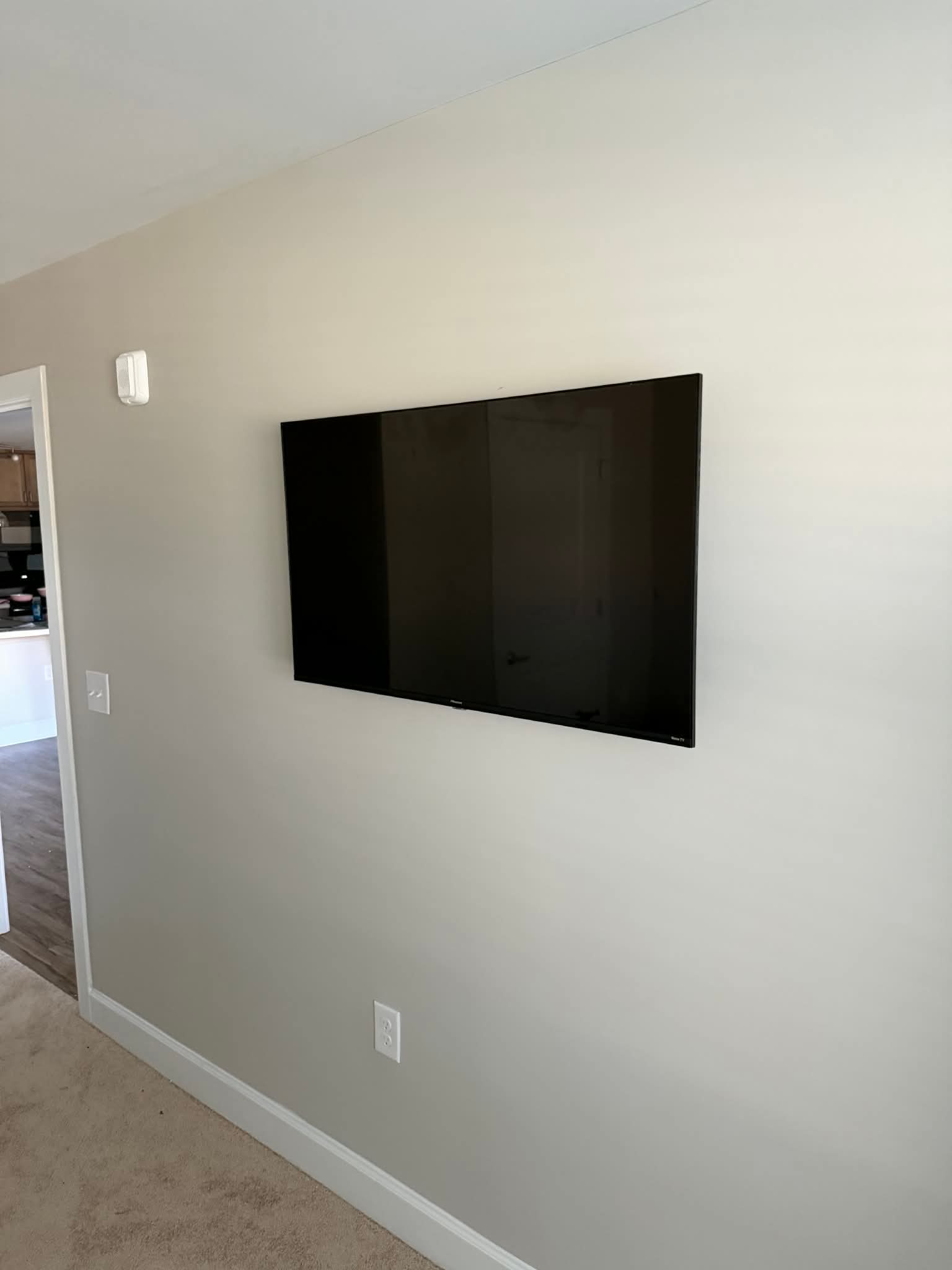 Premium mounted TV beside smart home control panel with neatly hidden wiring on a smooth painted wall