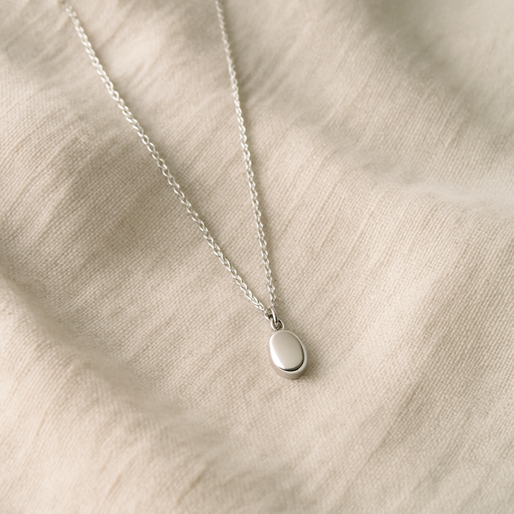 Delicate pendant necklace laid on neutral fabric
