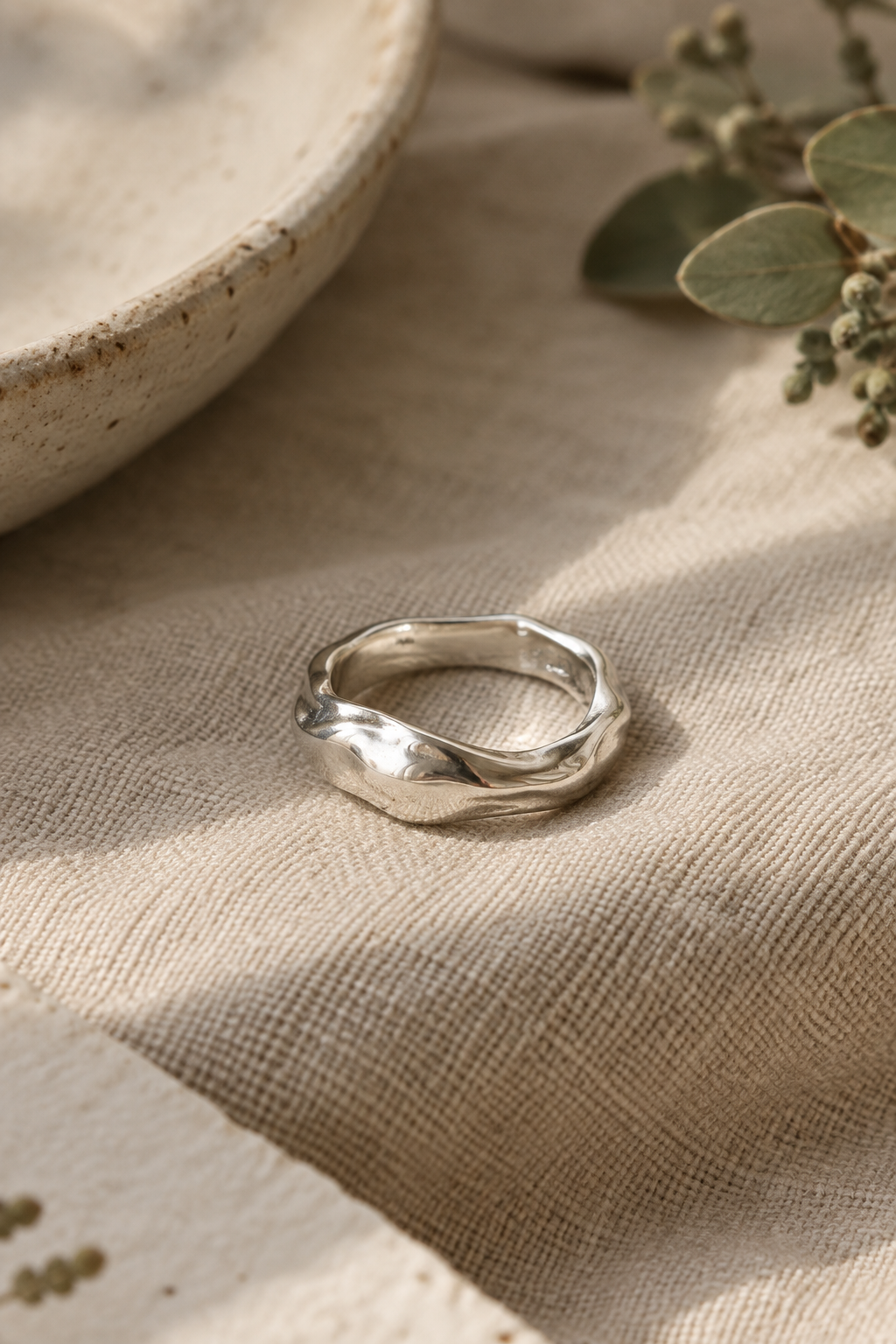 Handcrafted sculptural sterling silver ring resting on warm linen