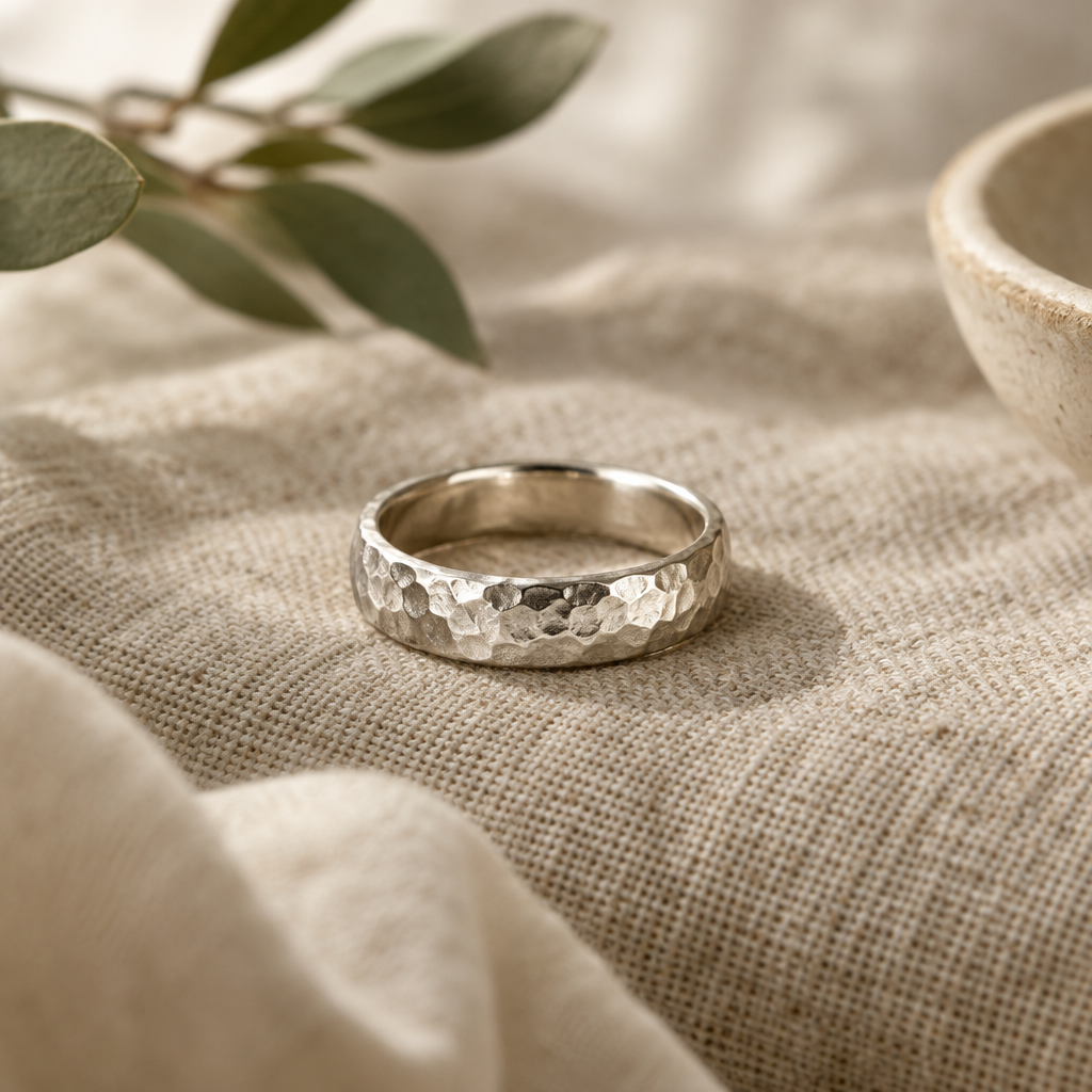 Handcrafted silver ring with a softly hammered finish resting on natural linen