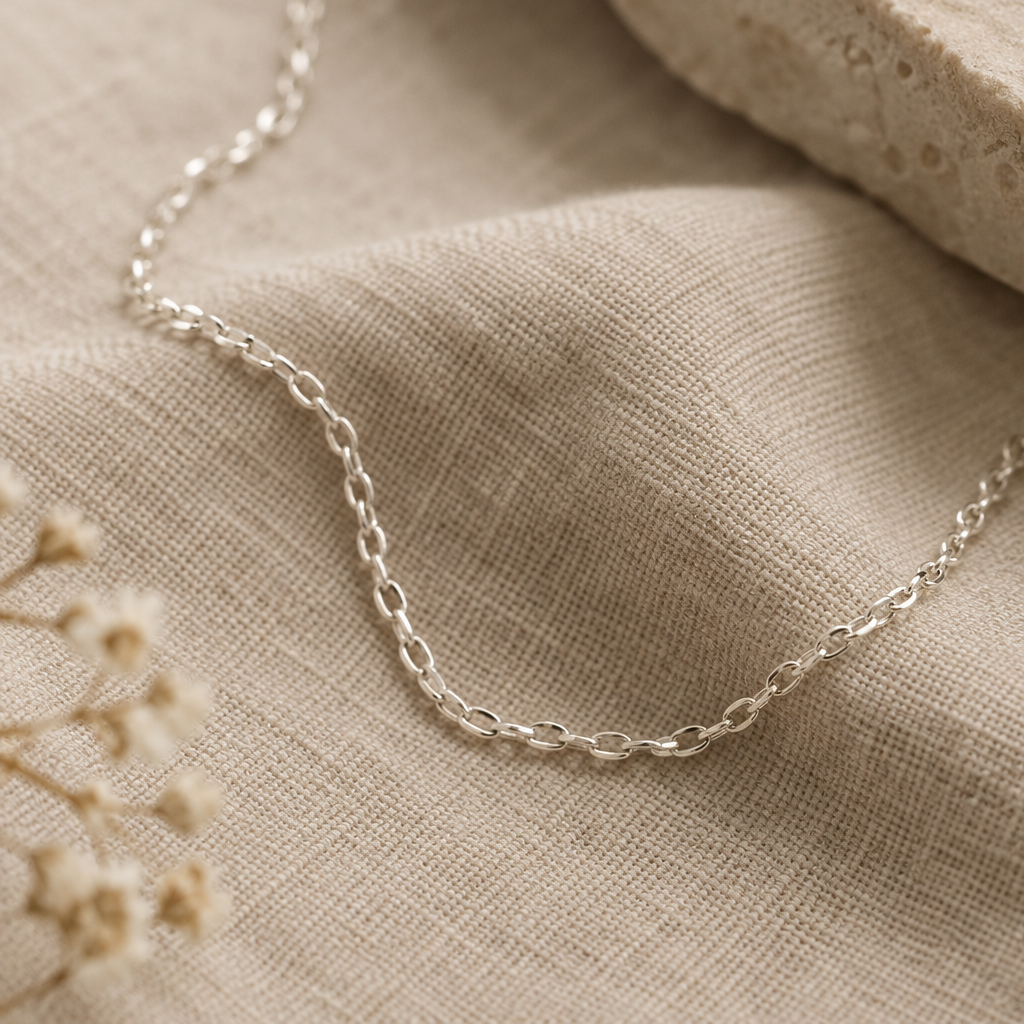 Close detail of a fine sterling silver chain on warm textured linen