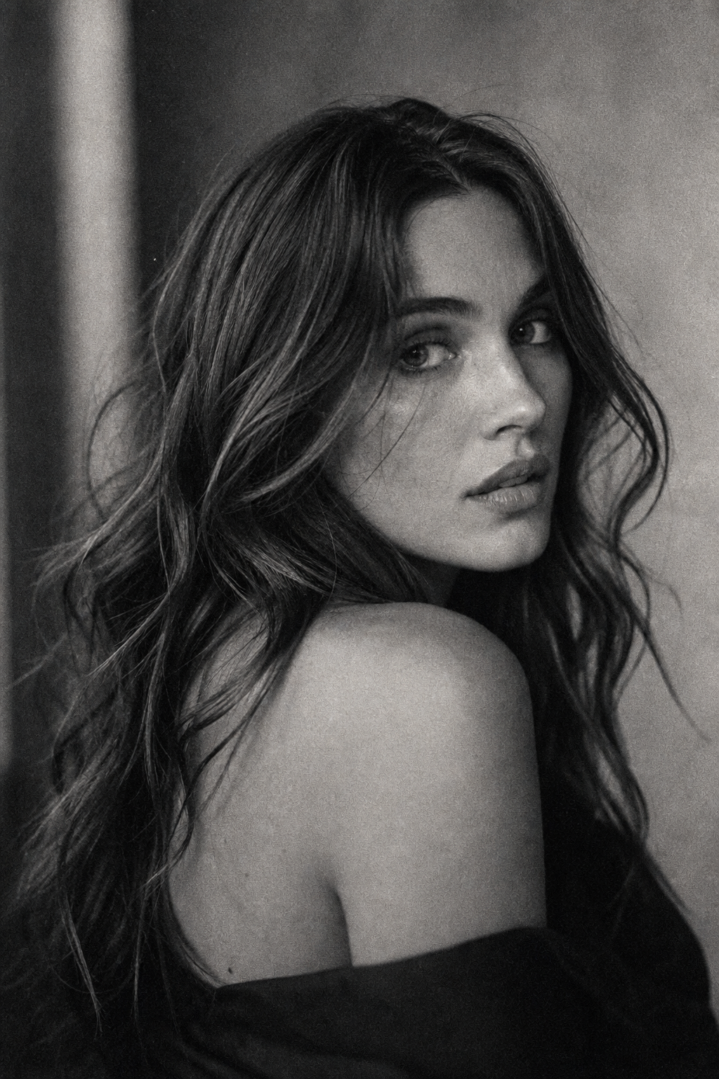 Moody black and white film grain portrait of a woman looking over her shoulder