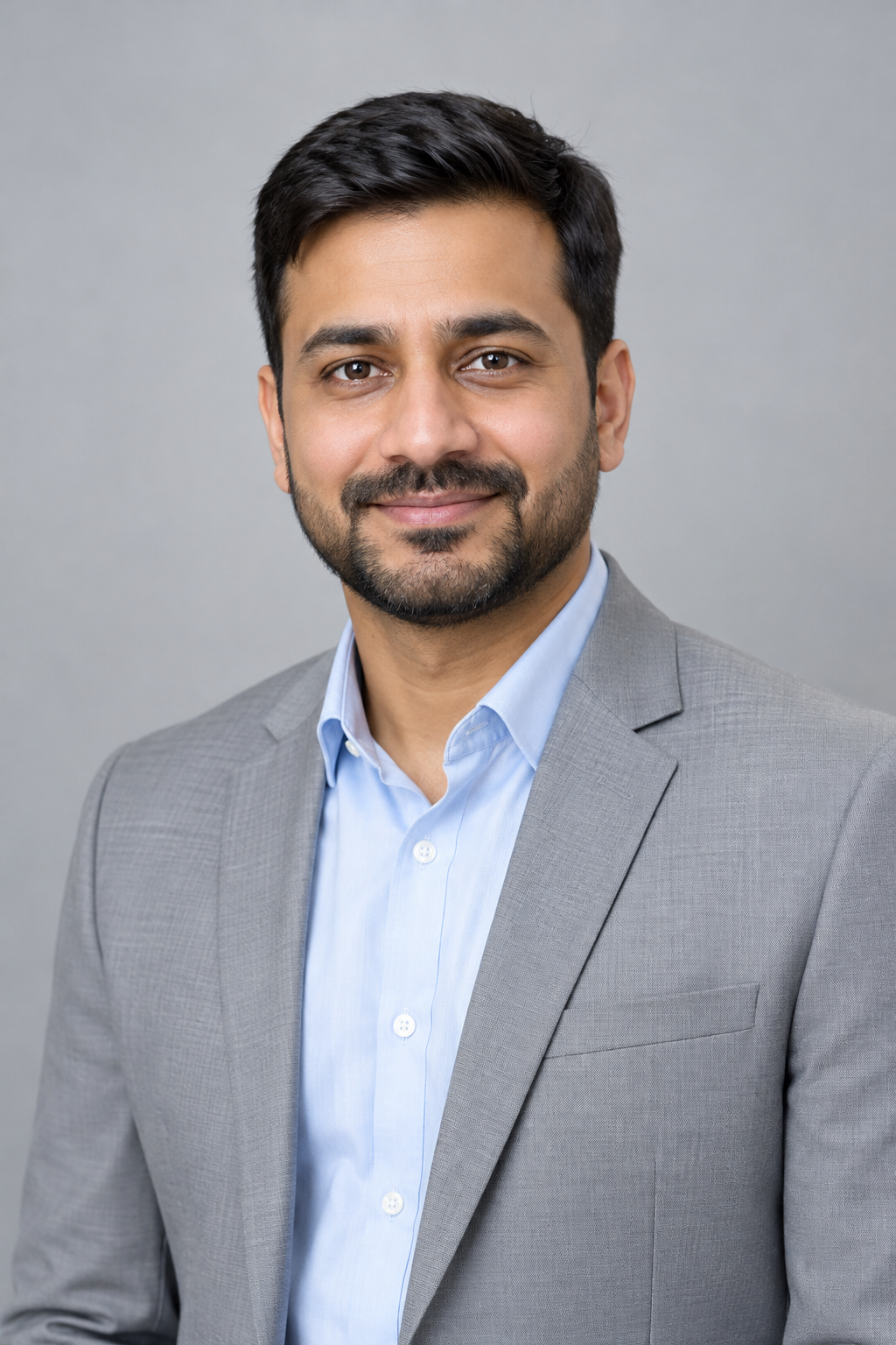 Professional headshot of Jordan Patel with short black hair, light gray suit, and soft studio backdrop