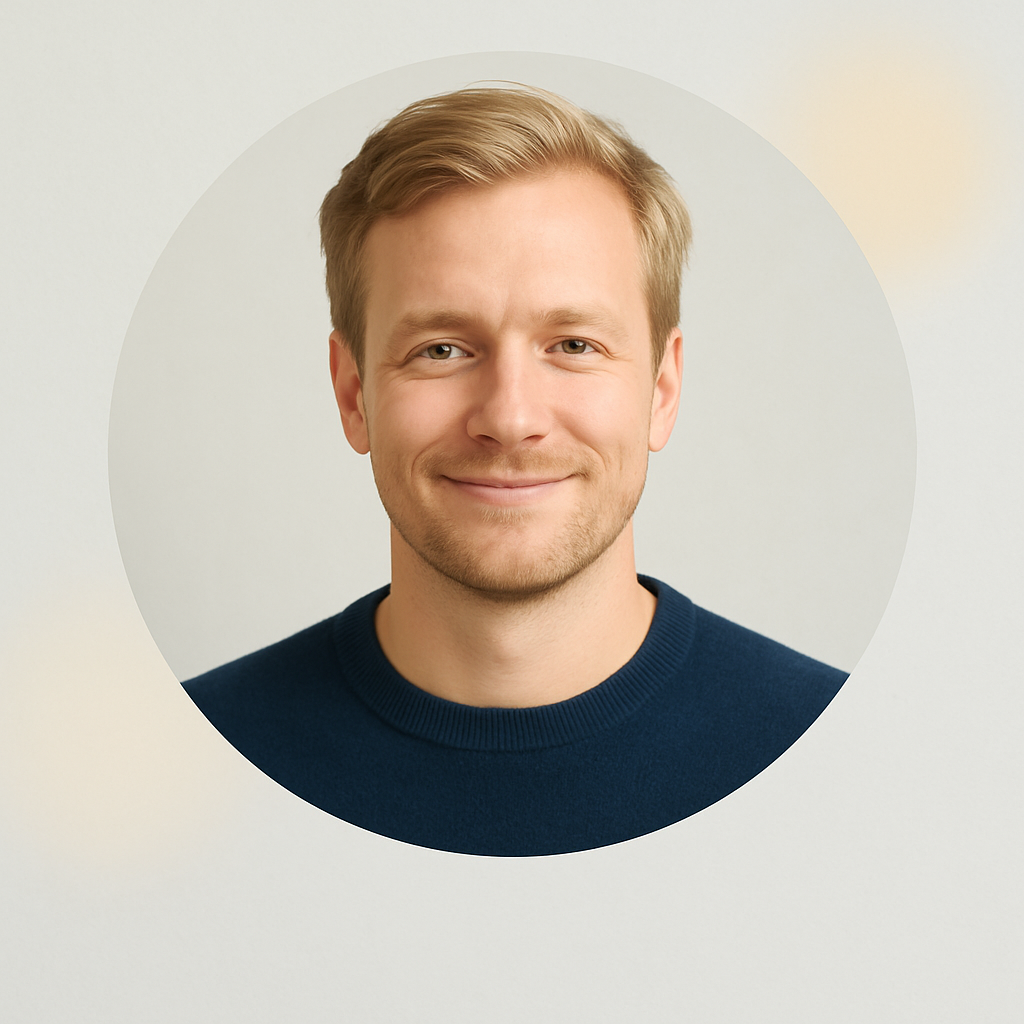 Portrait of Frederik Vestergaard, a man with blond hair, navy sweater, relaxed smile