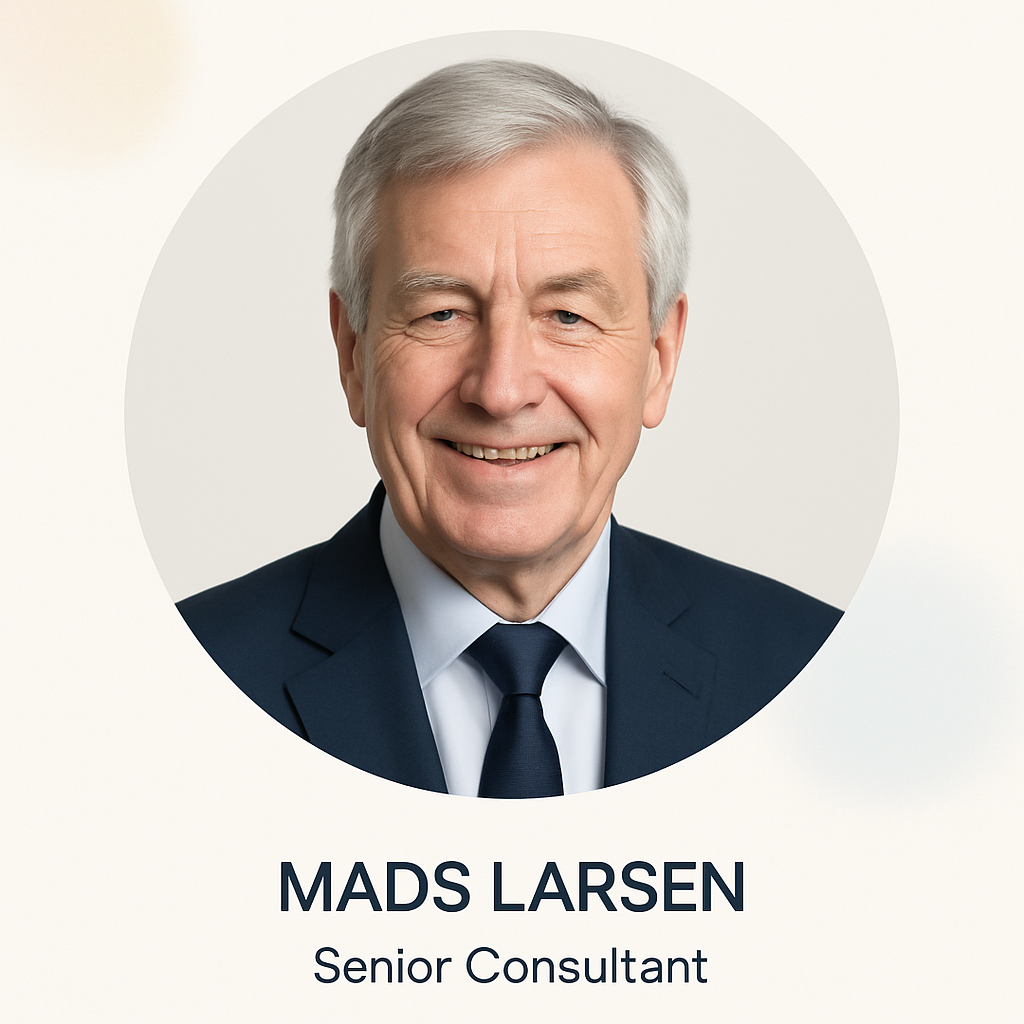Portrait of Mads Larsen, a senior man with gray hair in a navy suit and white shirt, smiling
